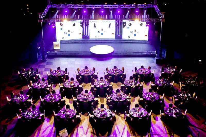 Aerial view of a gala dinner with purple lighting and stage screens