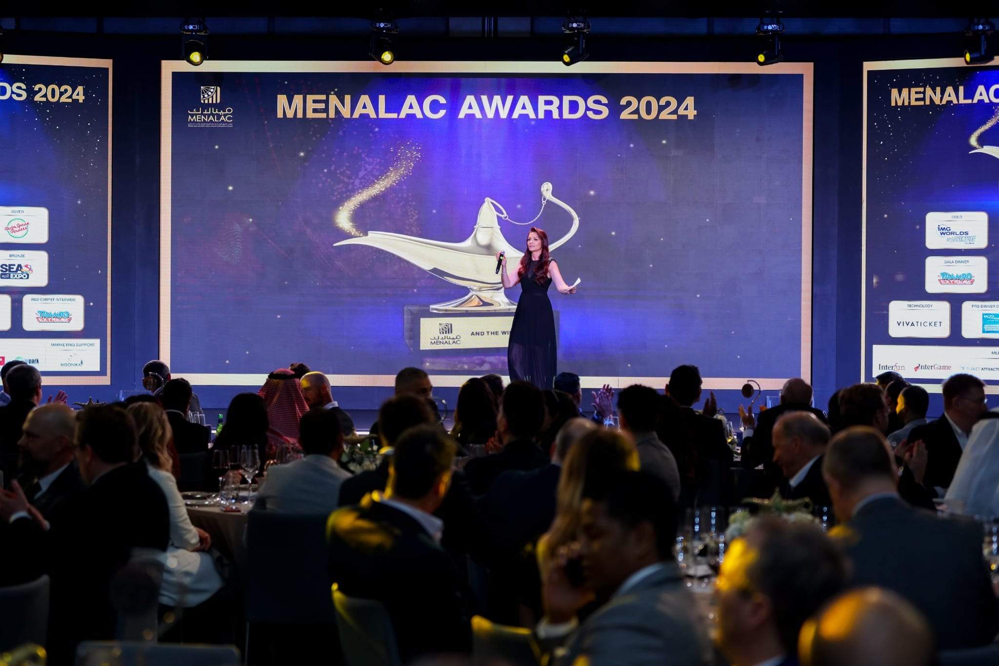 Host on stage opening an awards night in front of a full room