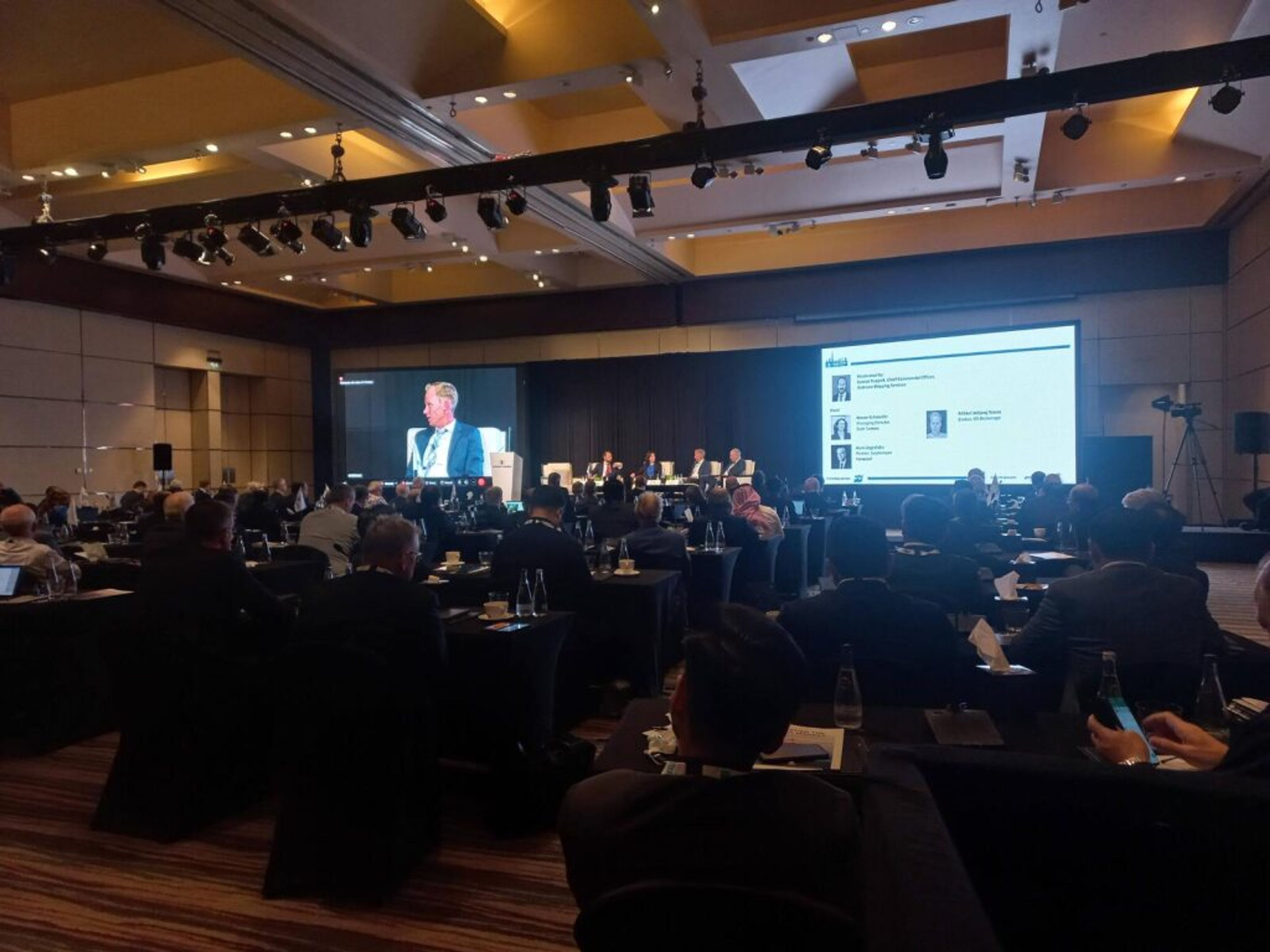 Audience at a corporate conference watching presenters on large screens