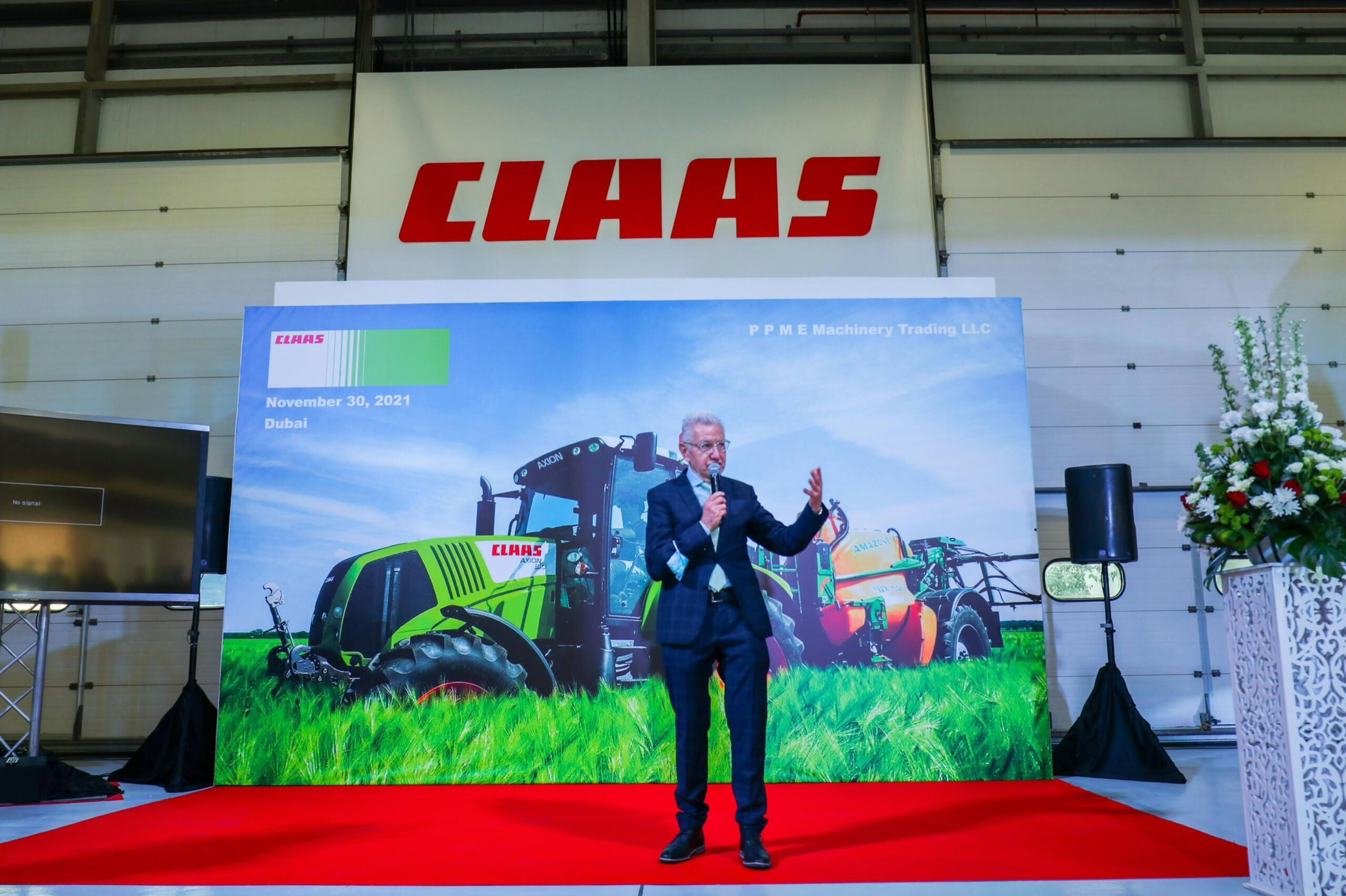 Presenter on stage in front of a large agricultural-themed brand backdrop