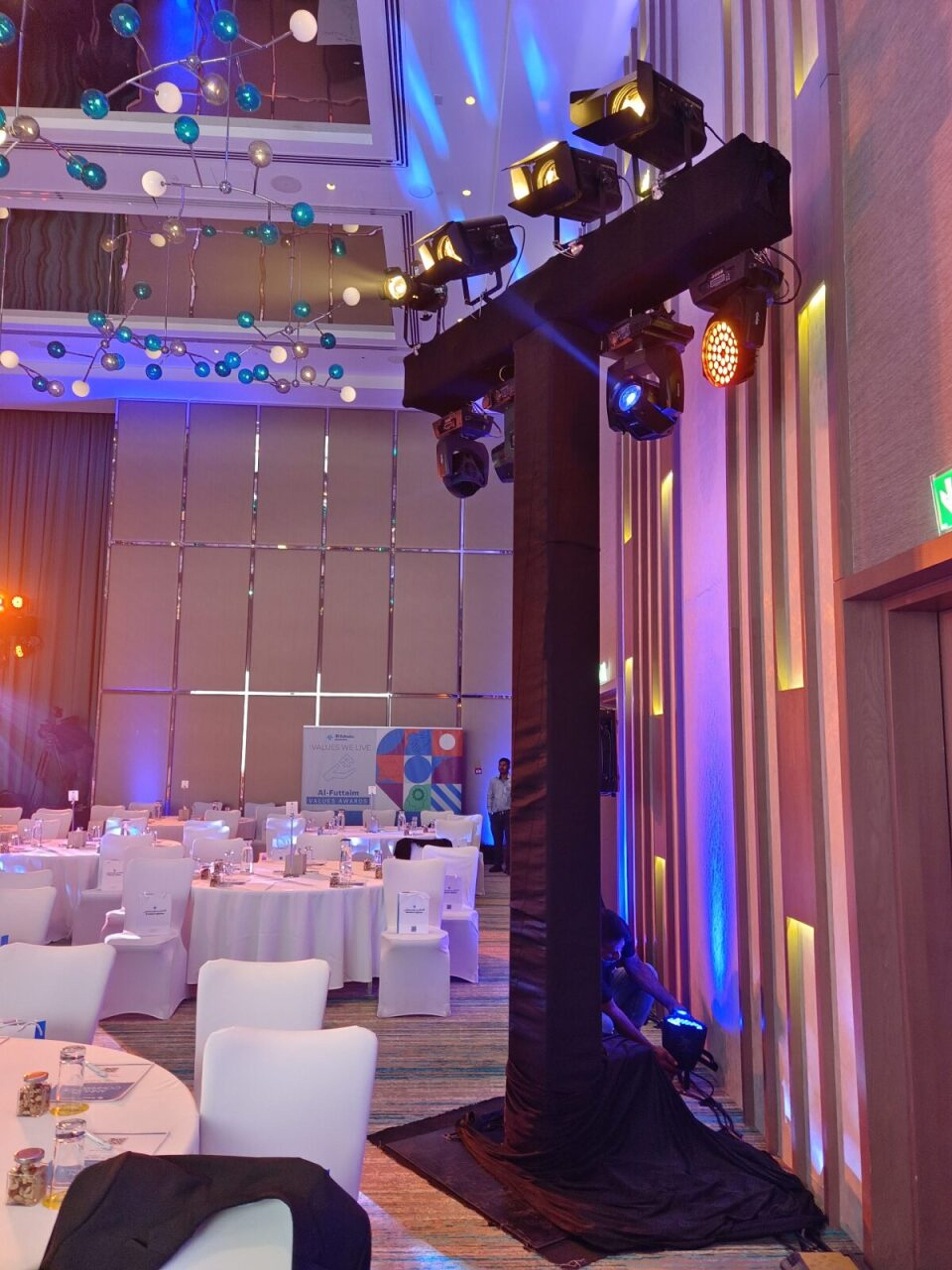 Moving-head lights and coloured uplighting rigged in a Dubai hotel ballroom set for a corporate dinner
