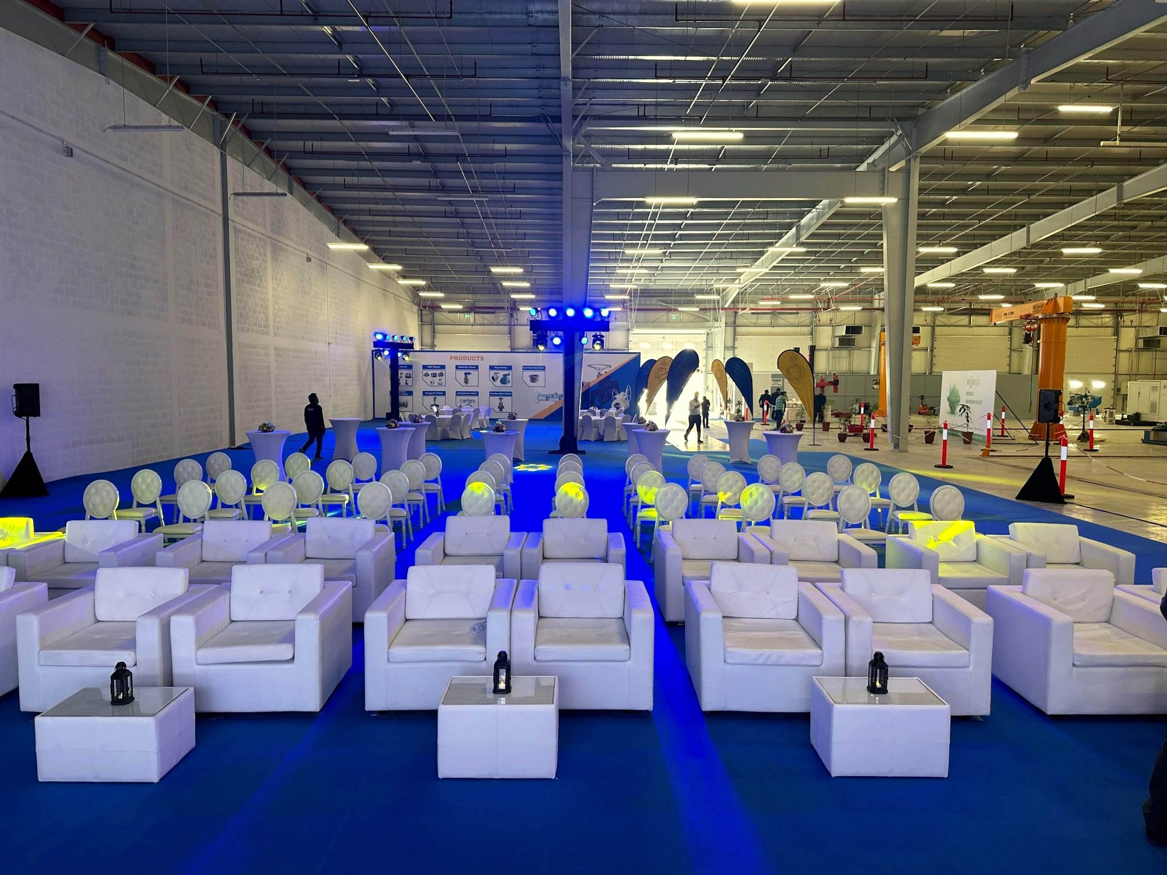 White lounge seating and a central aisle facing the stage inside the MT Group manufacturing unit launch, Abu Dhabi