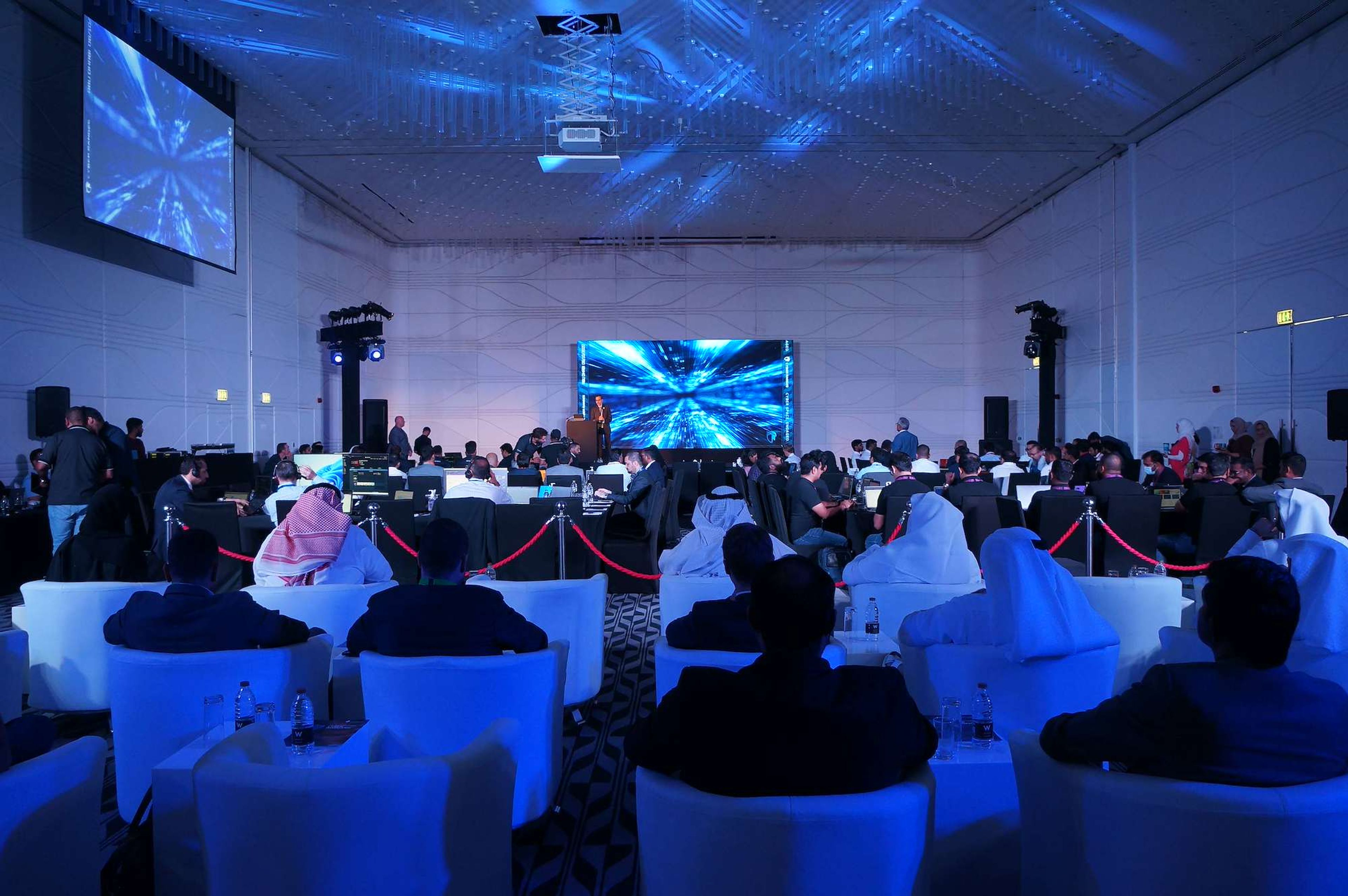 Corporate conference in an Abu Dhabi hotel ballroom with an LED screen, moving-head lighting and guests in lounge seating