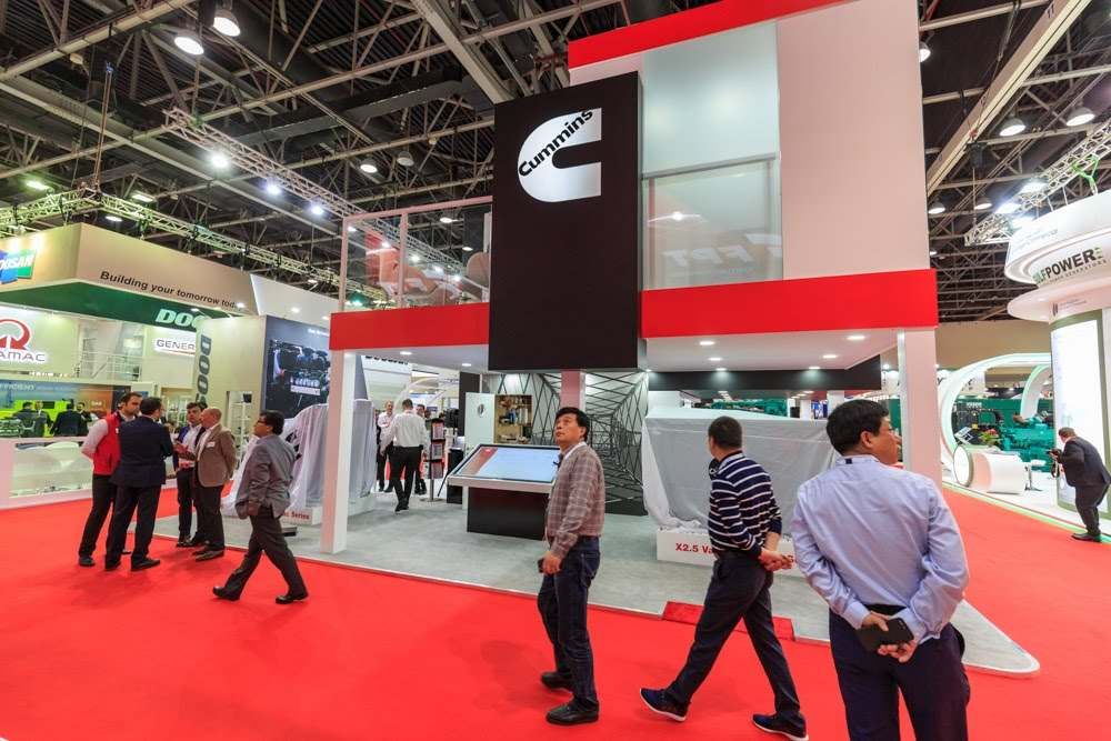 Visitors walking past a red and white branded exhibition stand