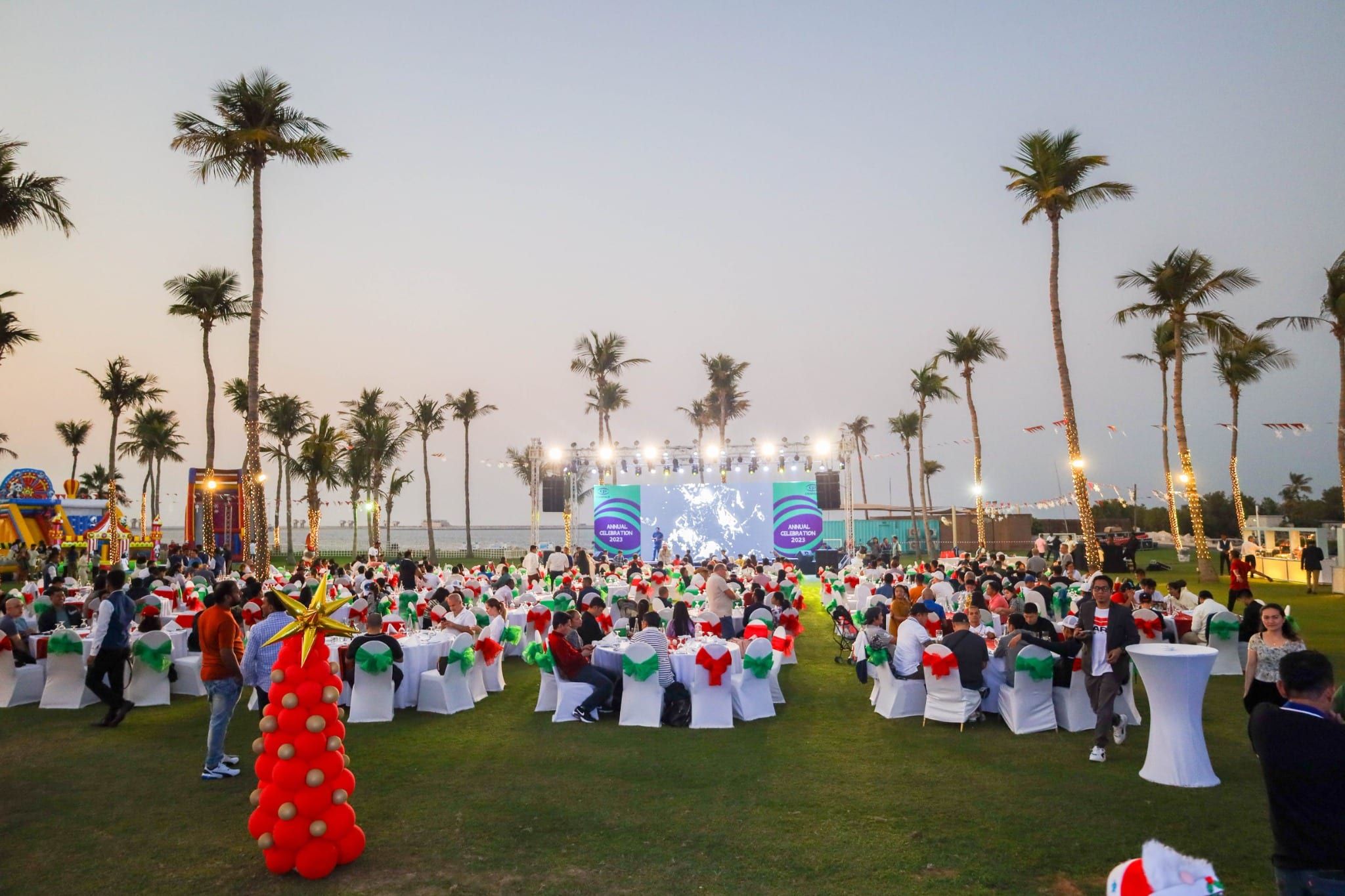 Guests on the lawn at sunset with the stage and palm trees behind