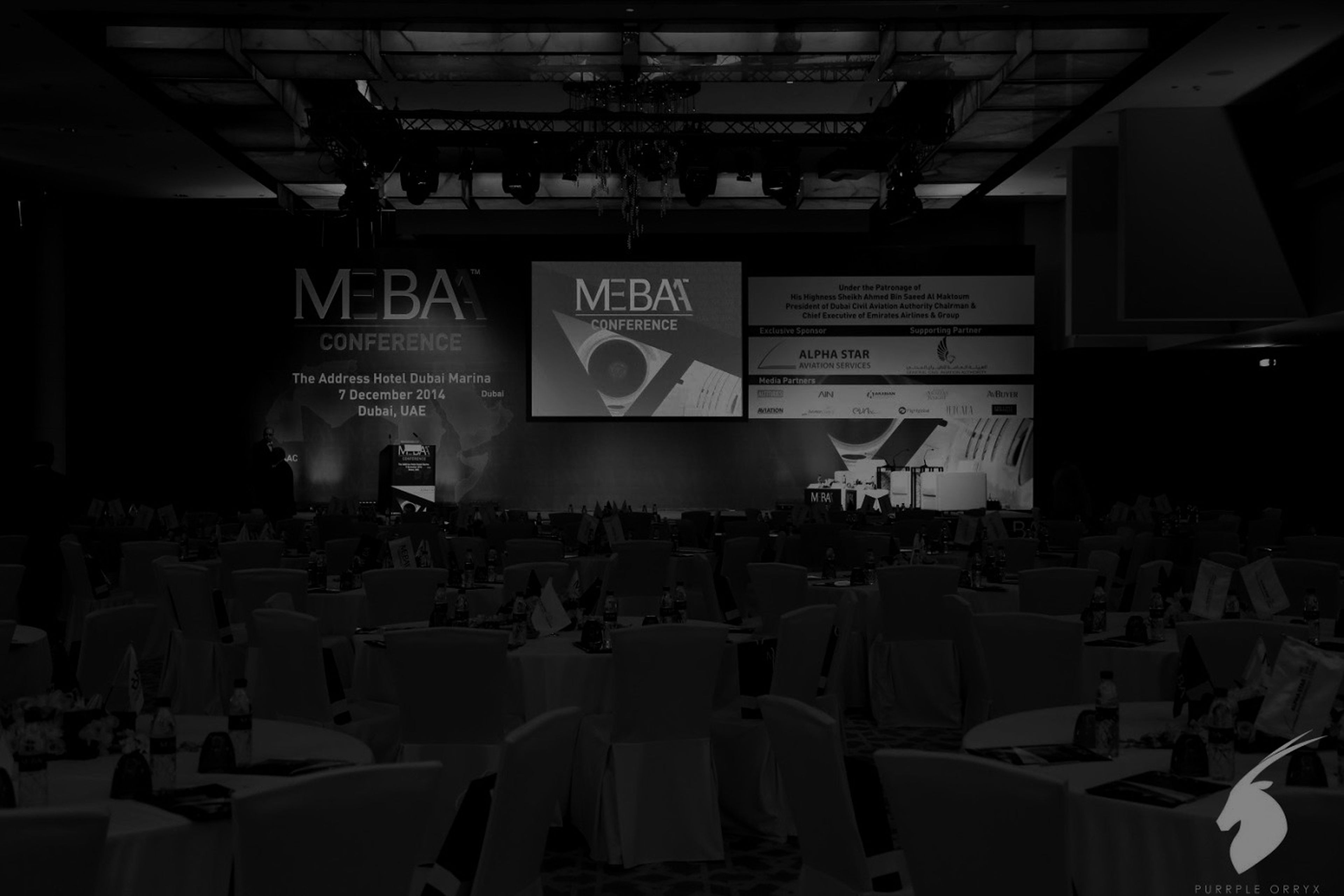 Hotel ballroom set for a corporate conference, with a branded stage, large projection screens and banquet seating