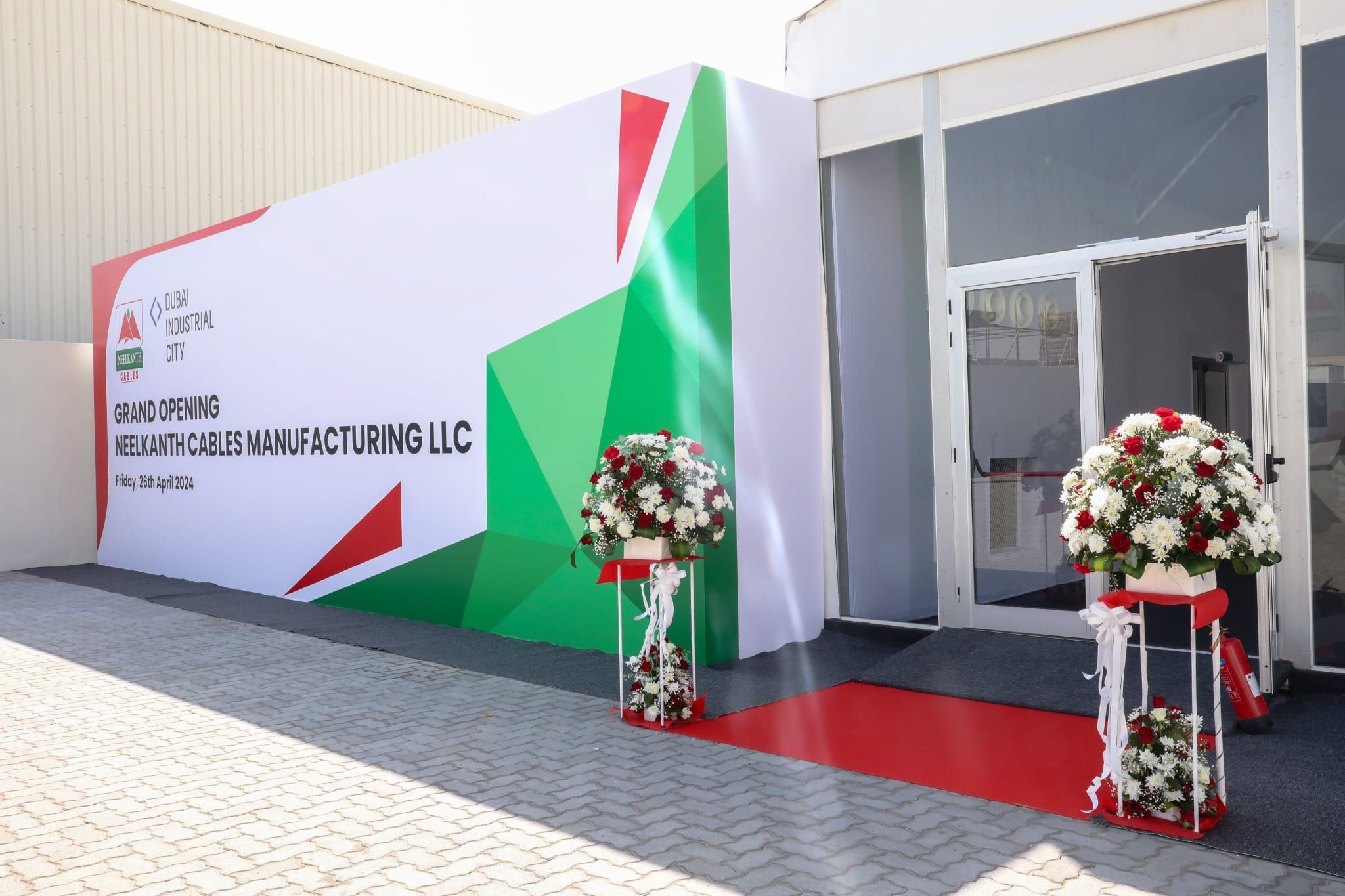 Branded entrance to the grand opening tent with red carpet and flower arrangements