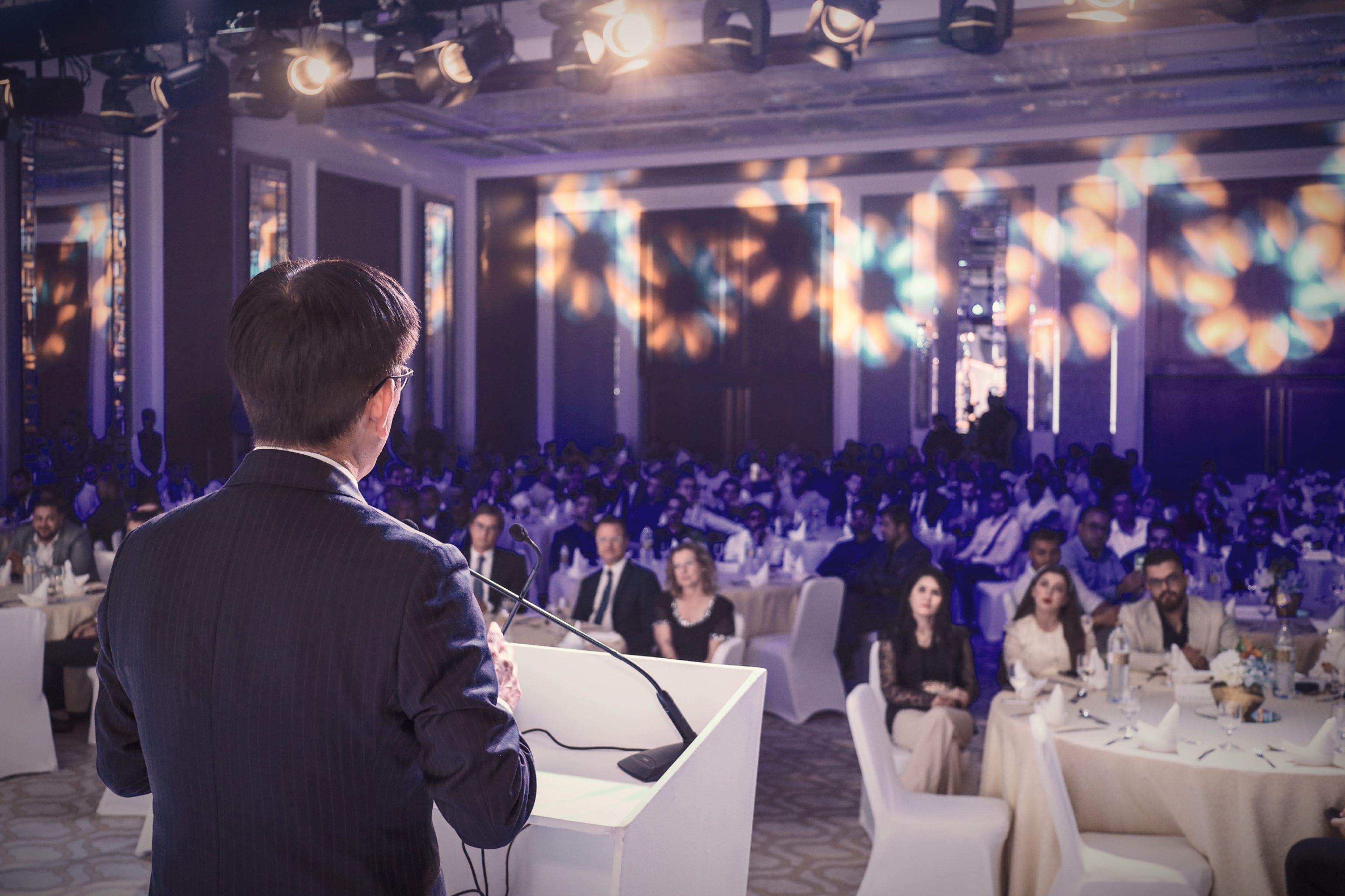 Speaker at a podium addressing guests at an evening gala dinner