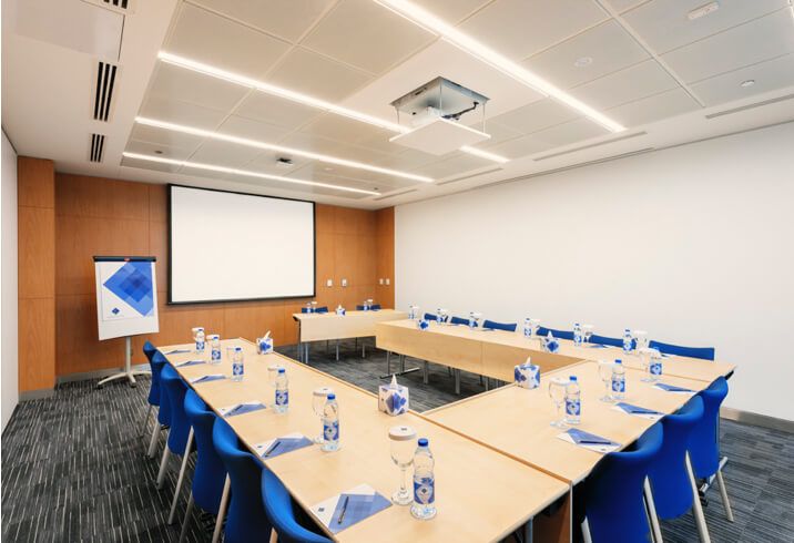 Boardroom-style meeting setup with a projection screen