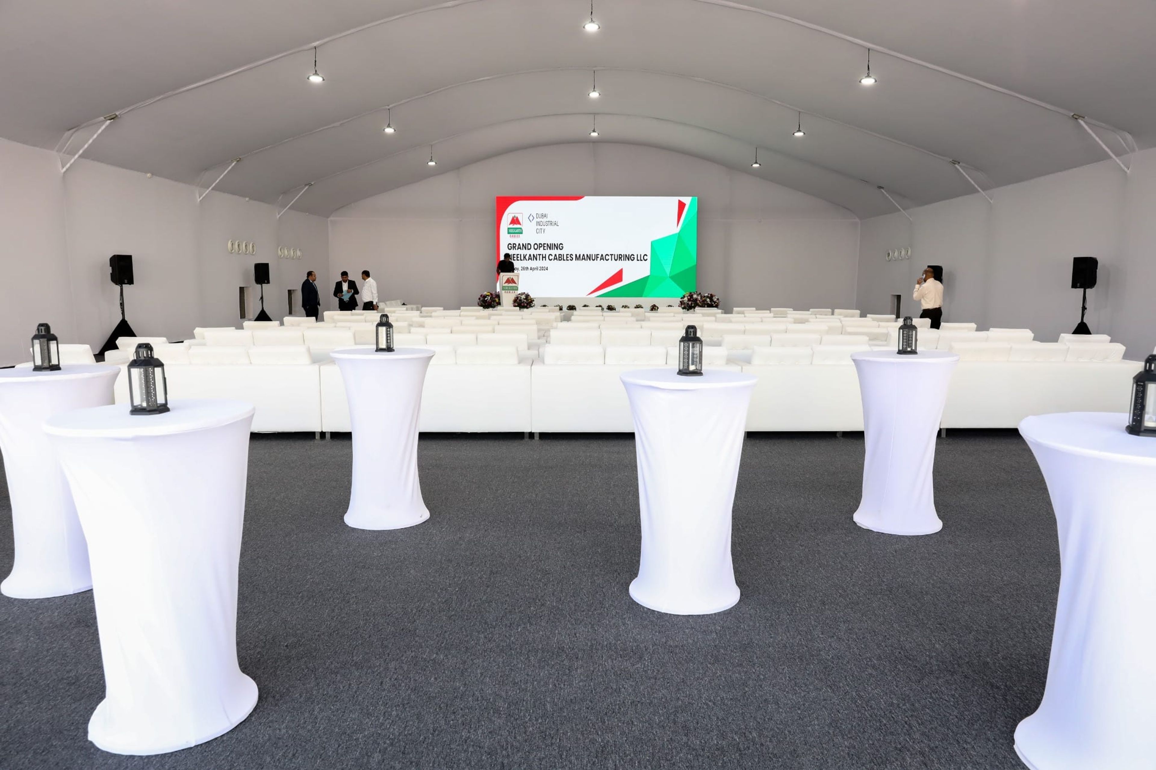 Tented venue with white cocktail tables and stage before the Neelkanth Cables grand opening