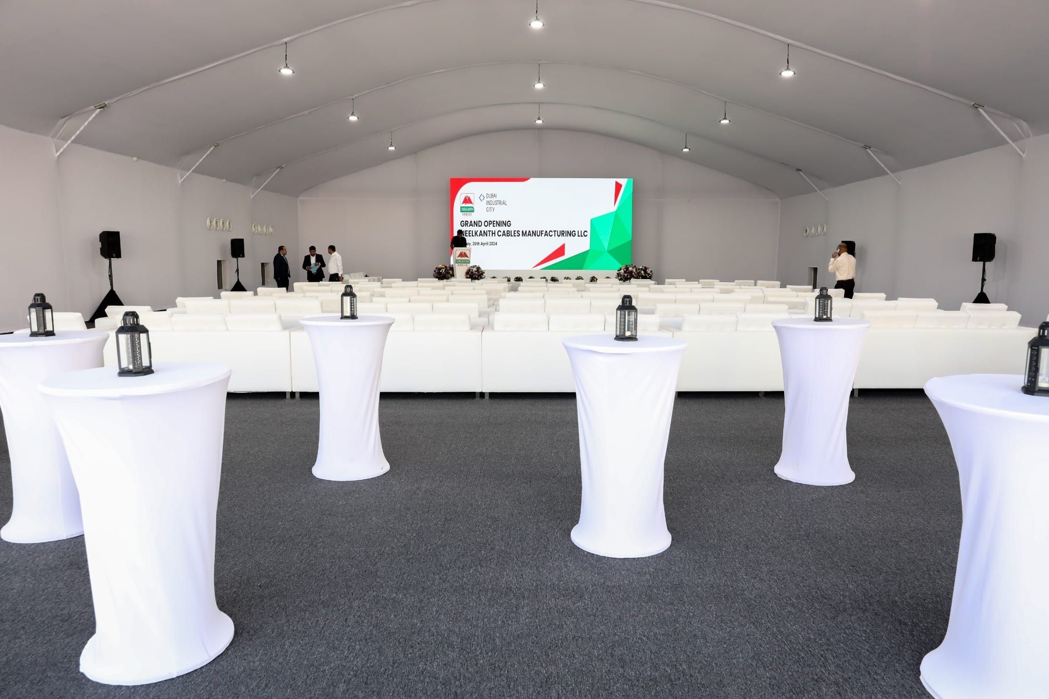 Tented venue with white cocktail tables and stage before the Neelkanth Cables grand opening