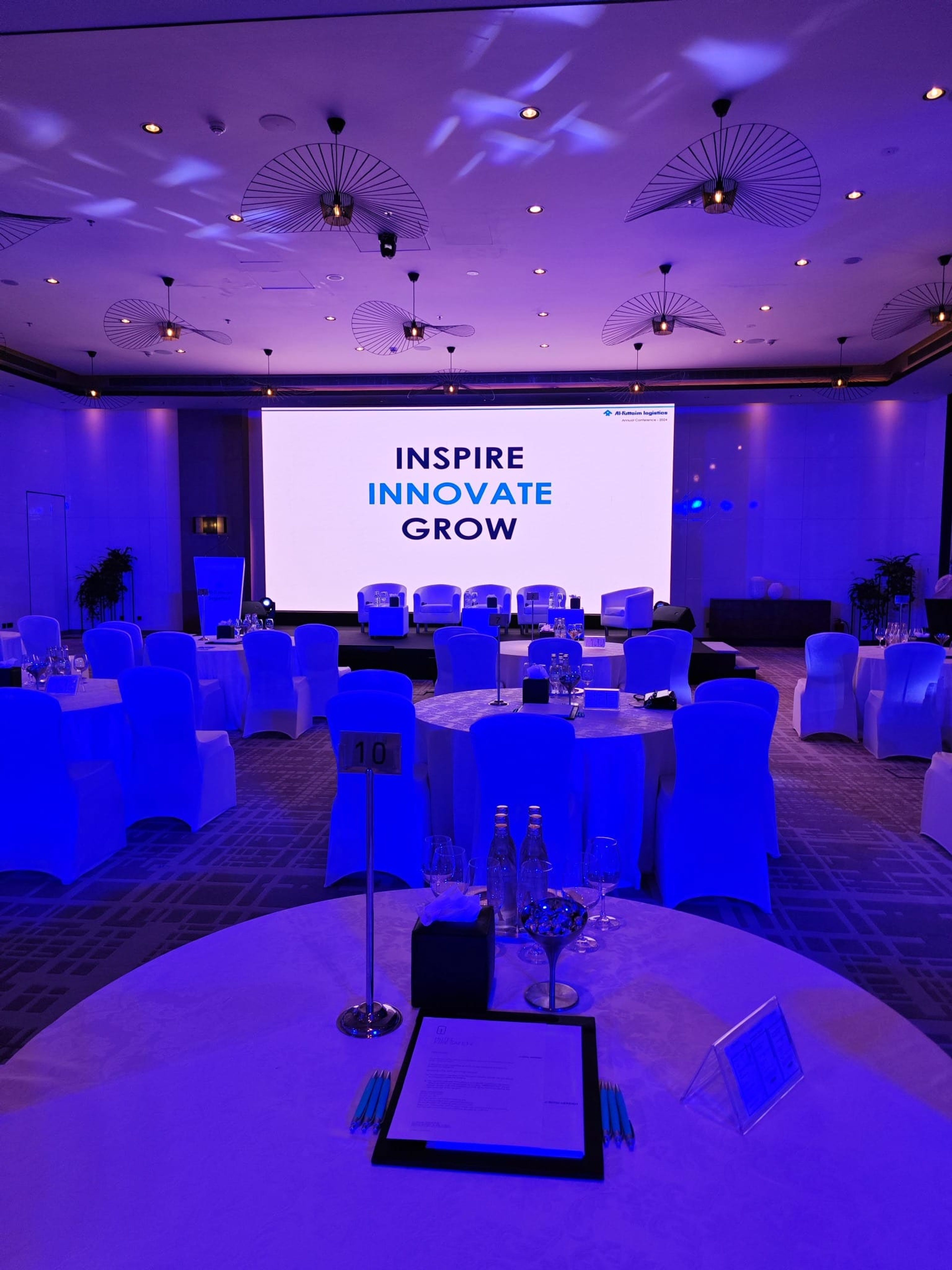 Inspire Innovate Grow conference theme on the stage screen, seen from a guest table