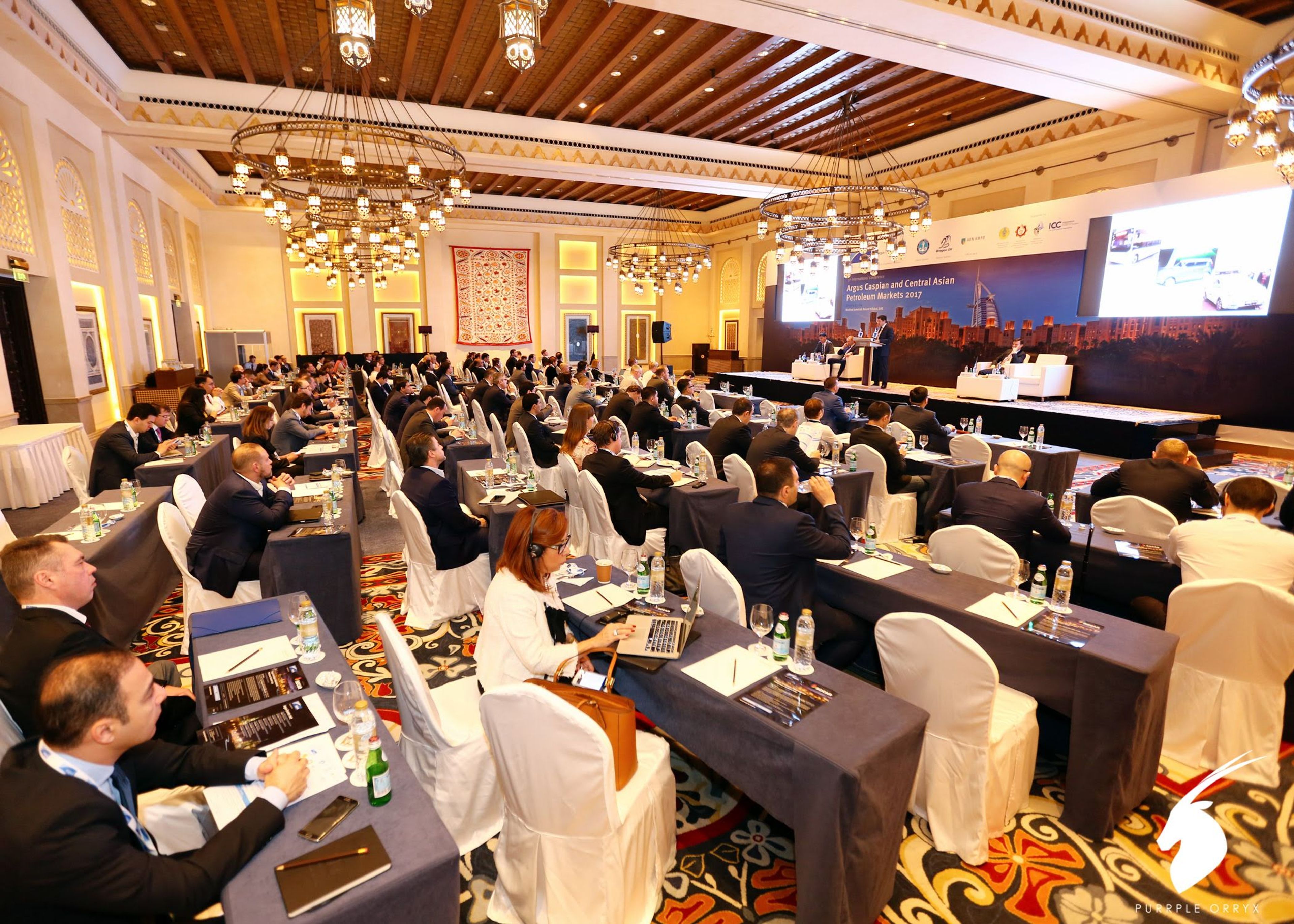 Delegates seated at a busy conference in a hotel ballroom