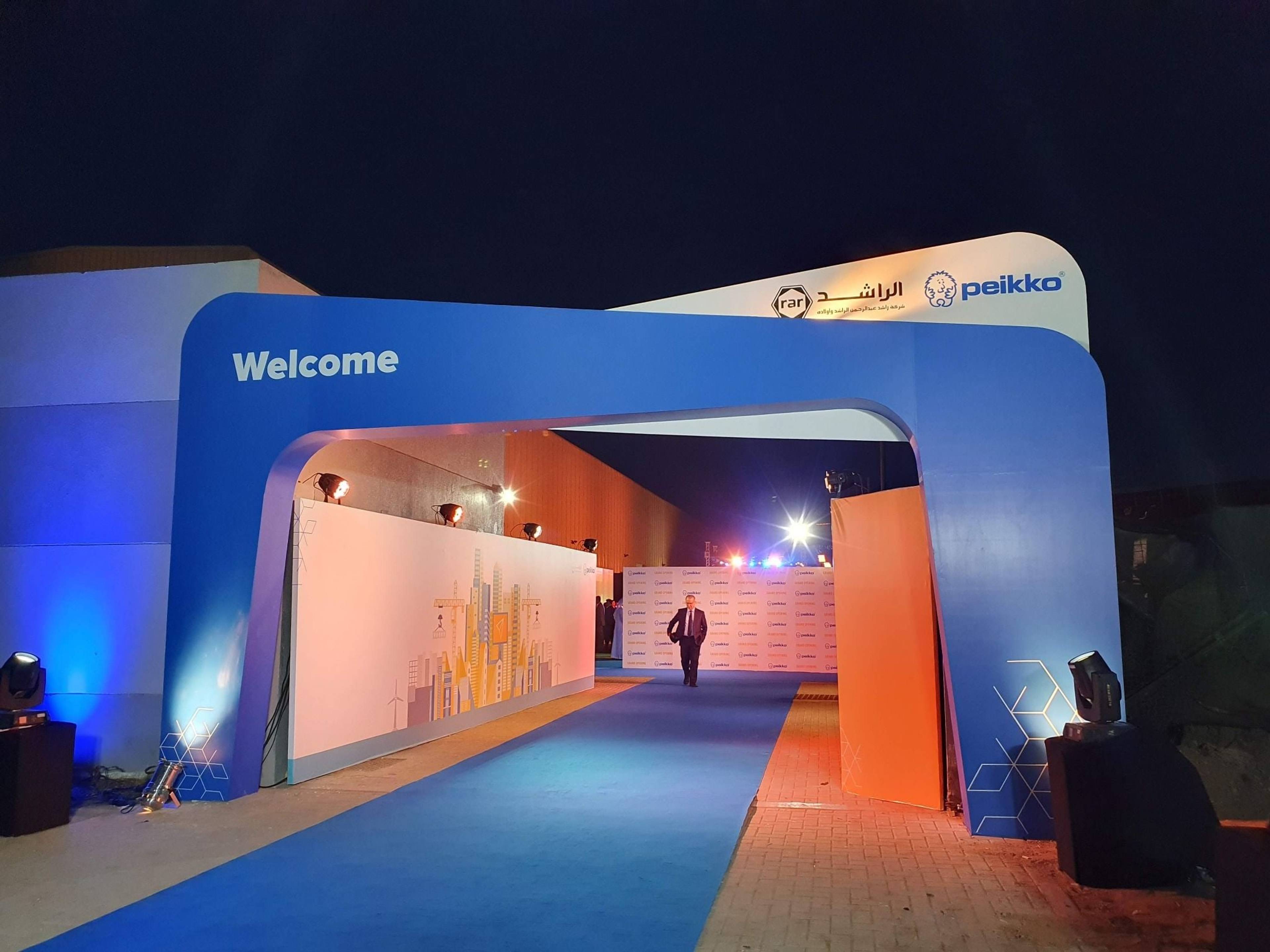 Branded welcome arch and blue carpet entrance at night for the Peikko facility grand opening in Ras Al Khaimah