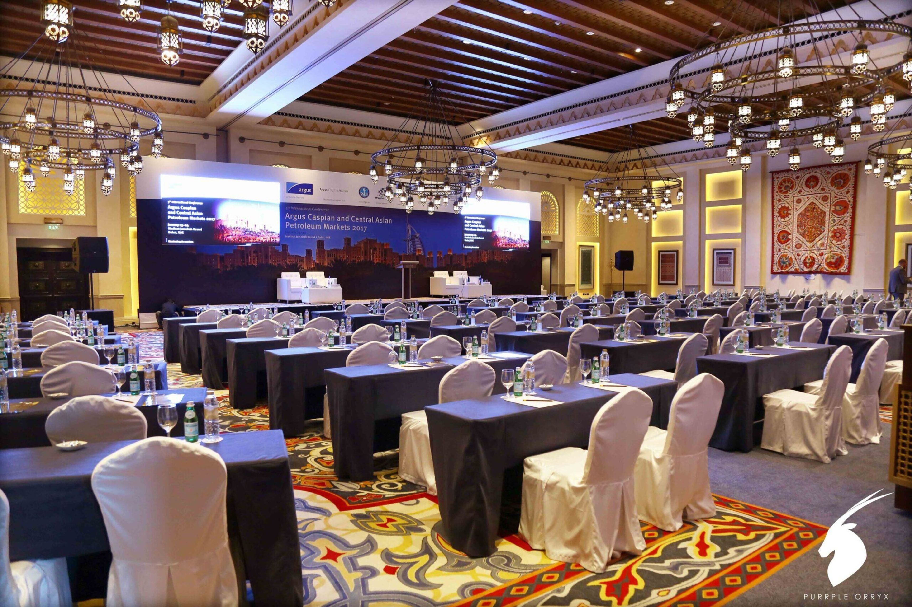 Conference ballroom with rows of chairs facing a stage and LED screen