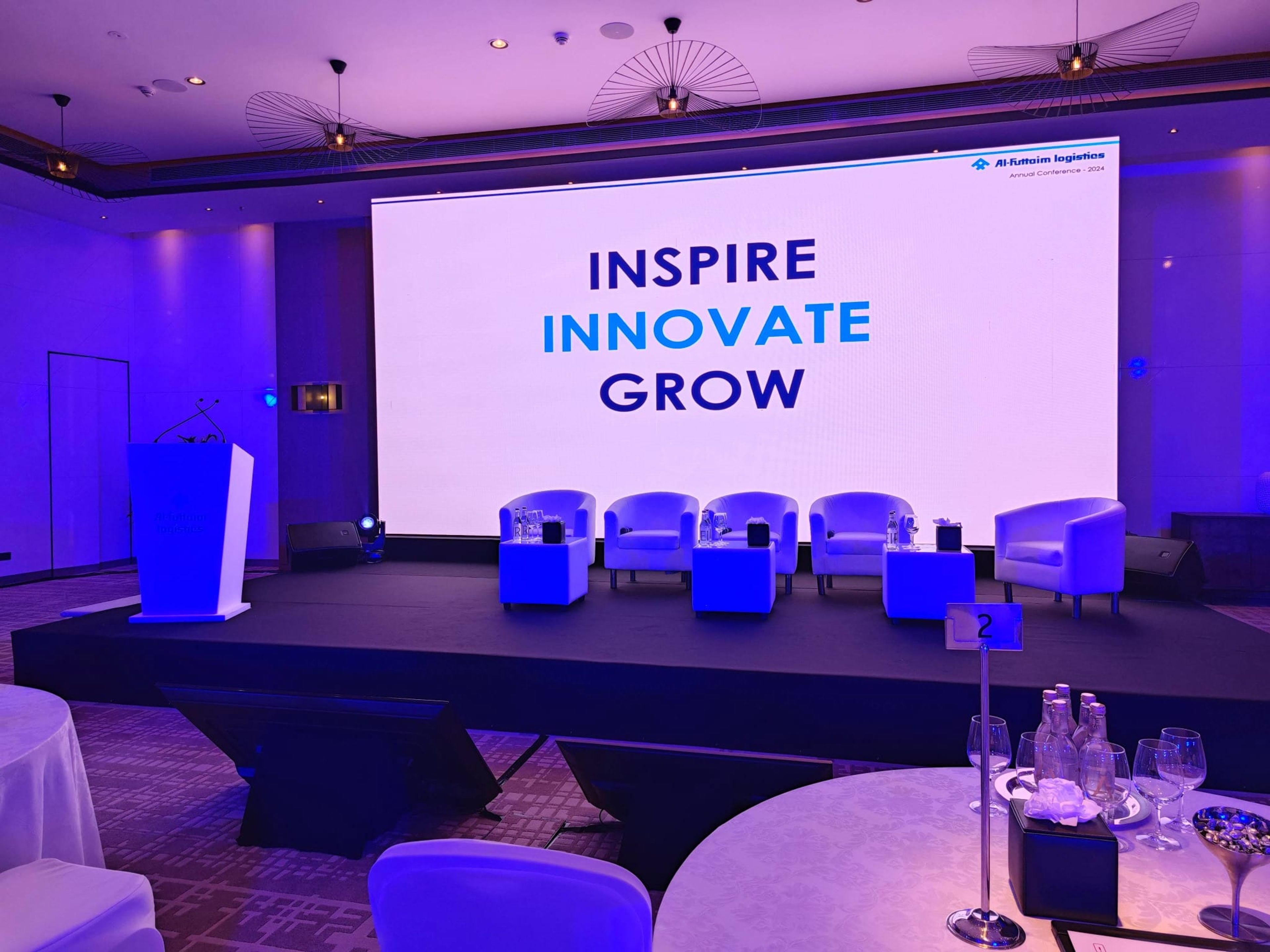 Conference stage with the Inspire Innovate Grow LED screen, panel lounge chairs and lectern