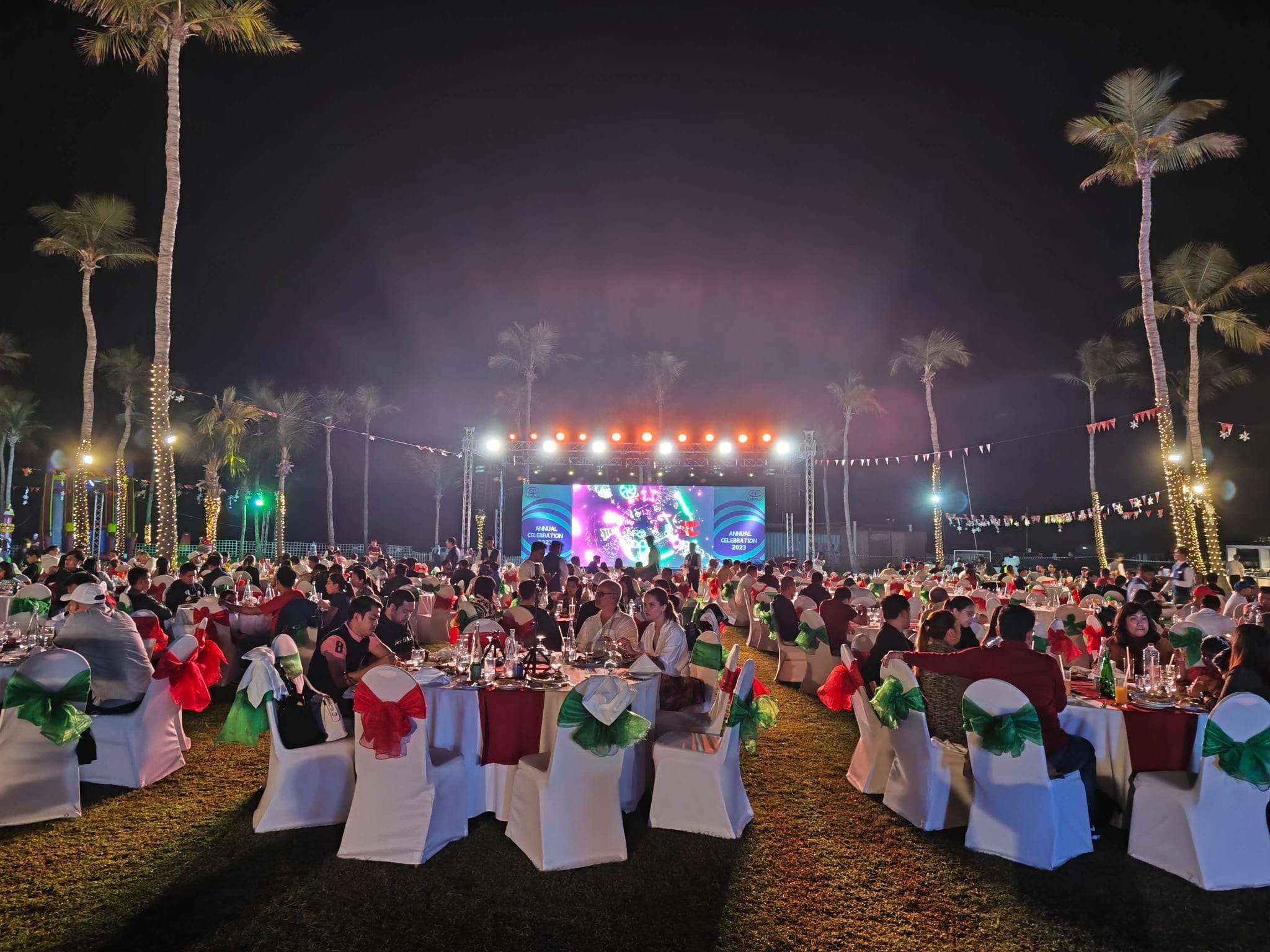 Evening view of guest tables and a lit stage at a family day