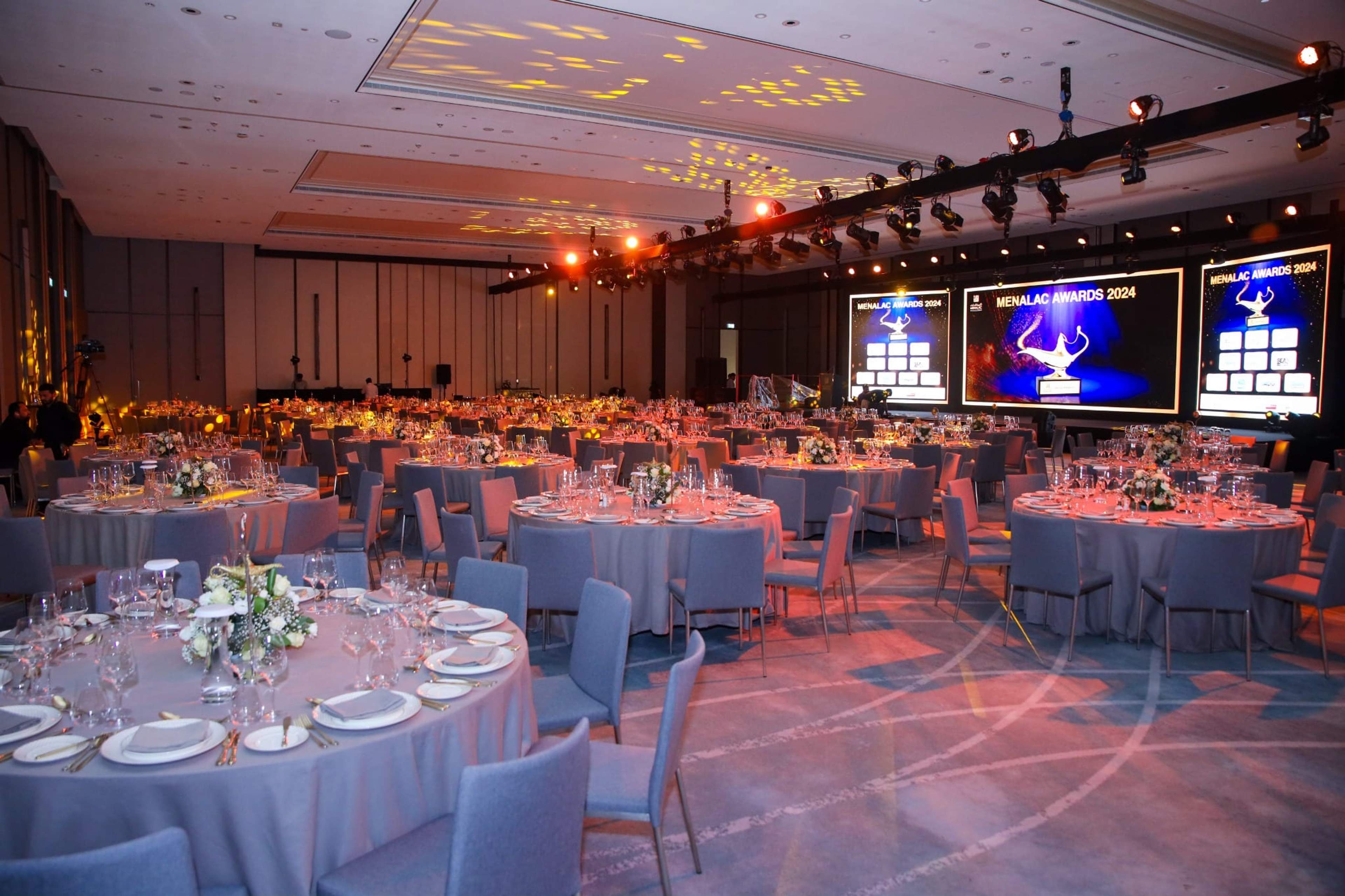 Gala dinner tables with floral centrepieces and stage screens before guests arrive