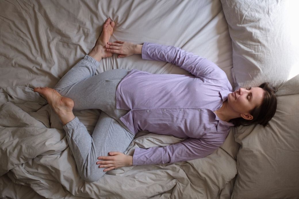 Une femme aux cheveux bruns courts se repose sur un lit en plein jour.