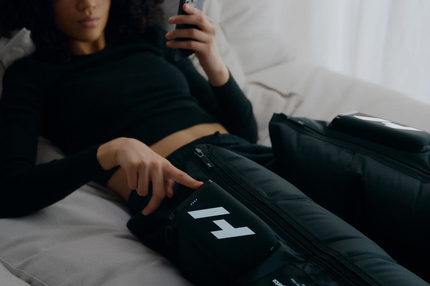 A patient lying back wearing Hyperice Normatec Elite leg boots