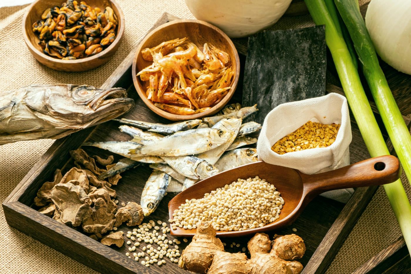 A wooden tray of dried fish, shrimp, ginger, mushrooms and grains used in food therapy