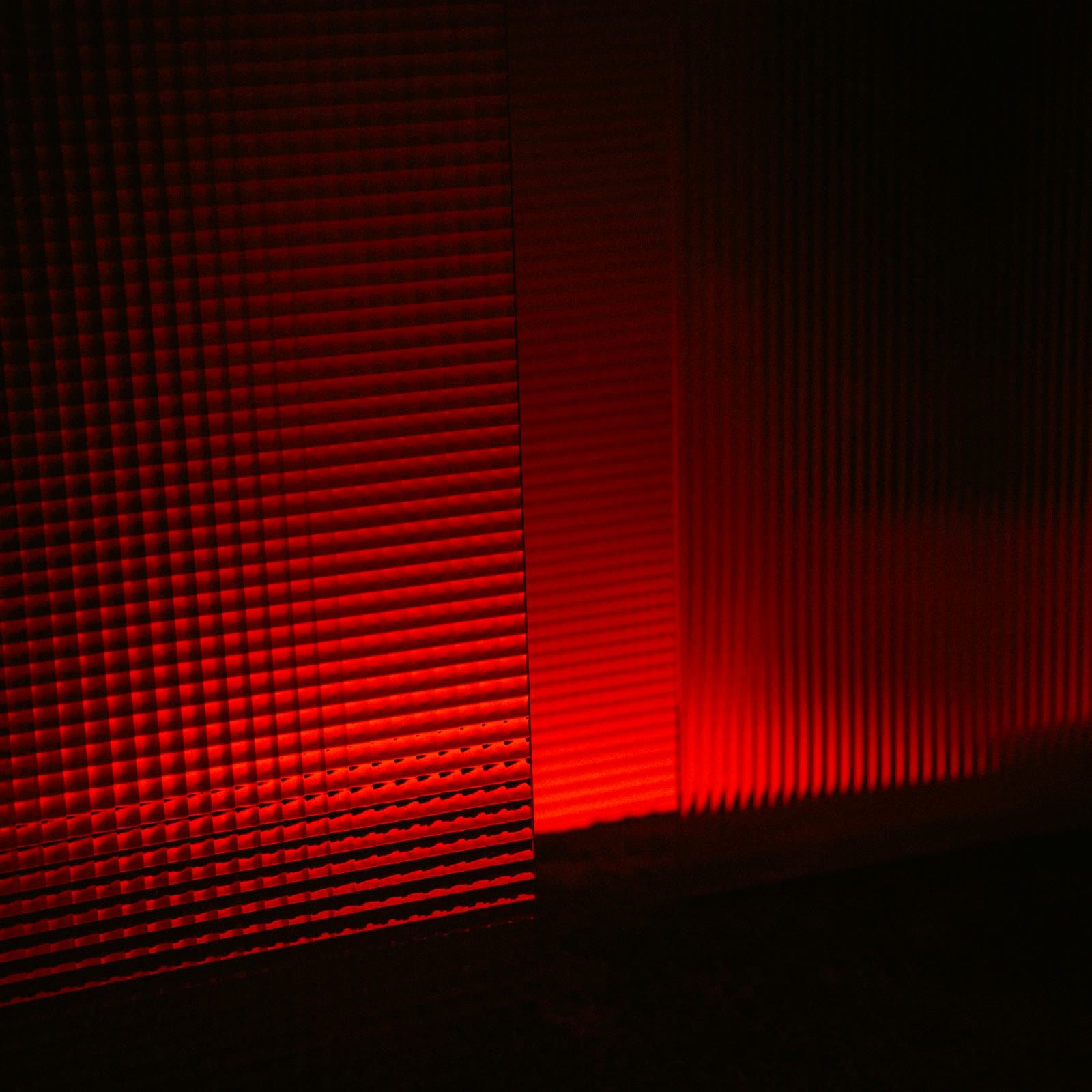 A red light therapy panel glowing in a dark room