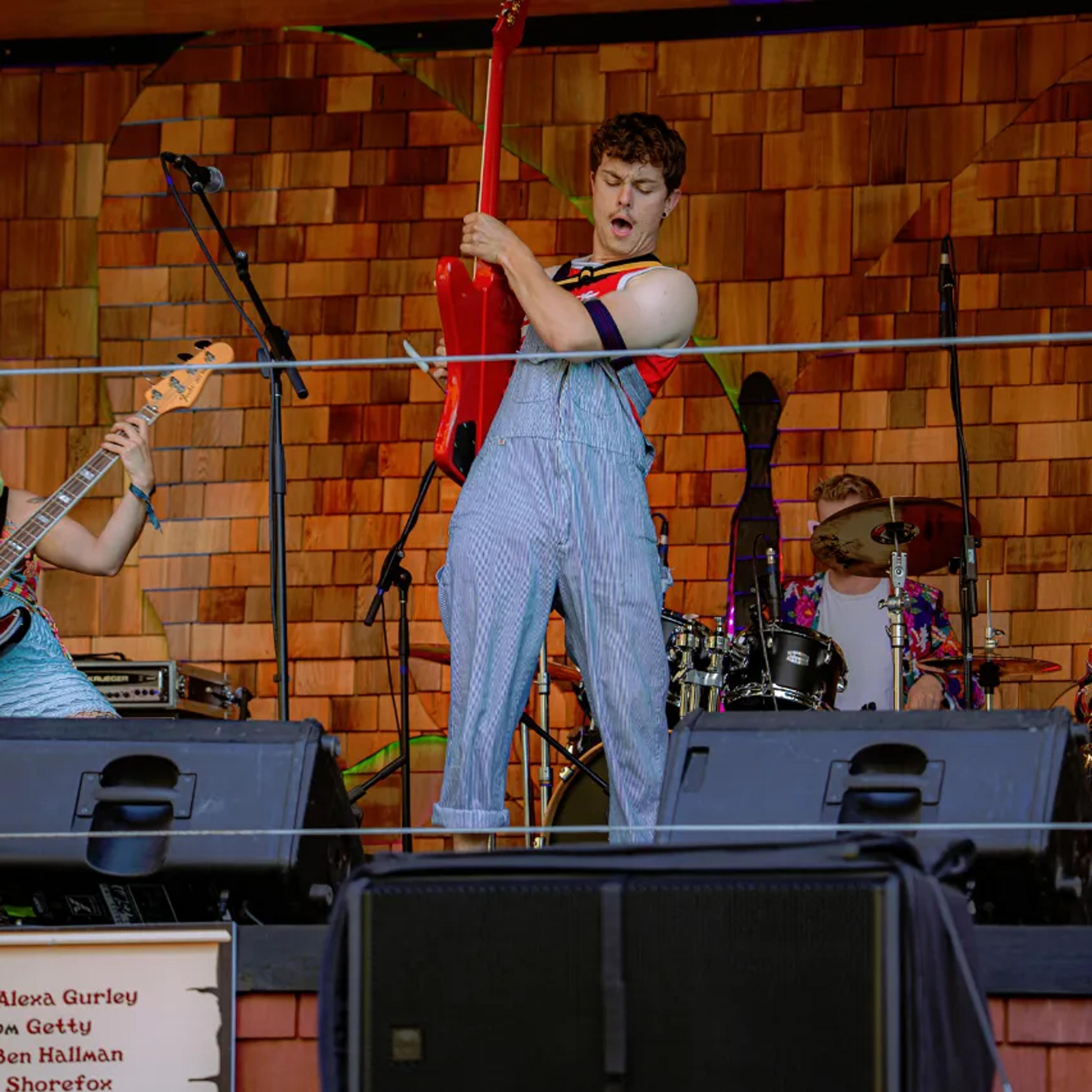 Live band with bass, vocals, drums, and saxophone on AgeHa stage.