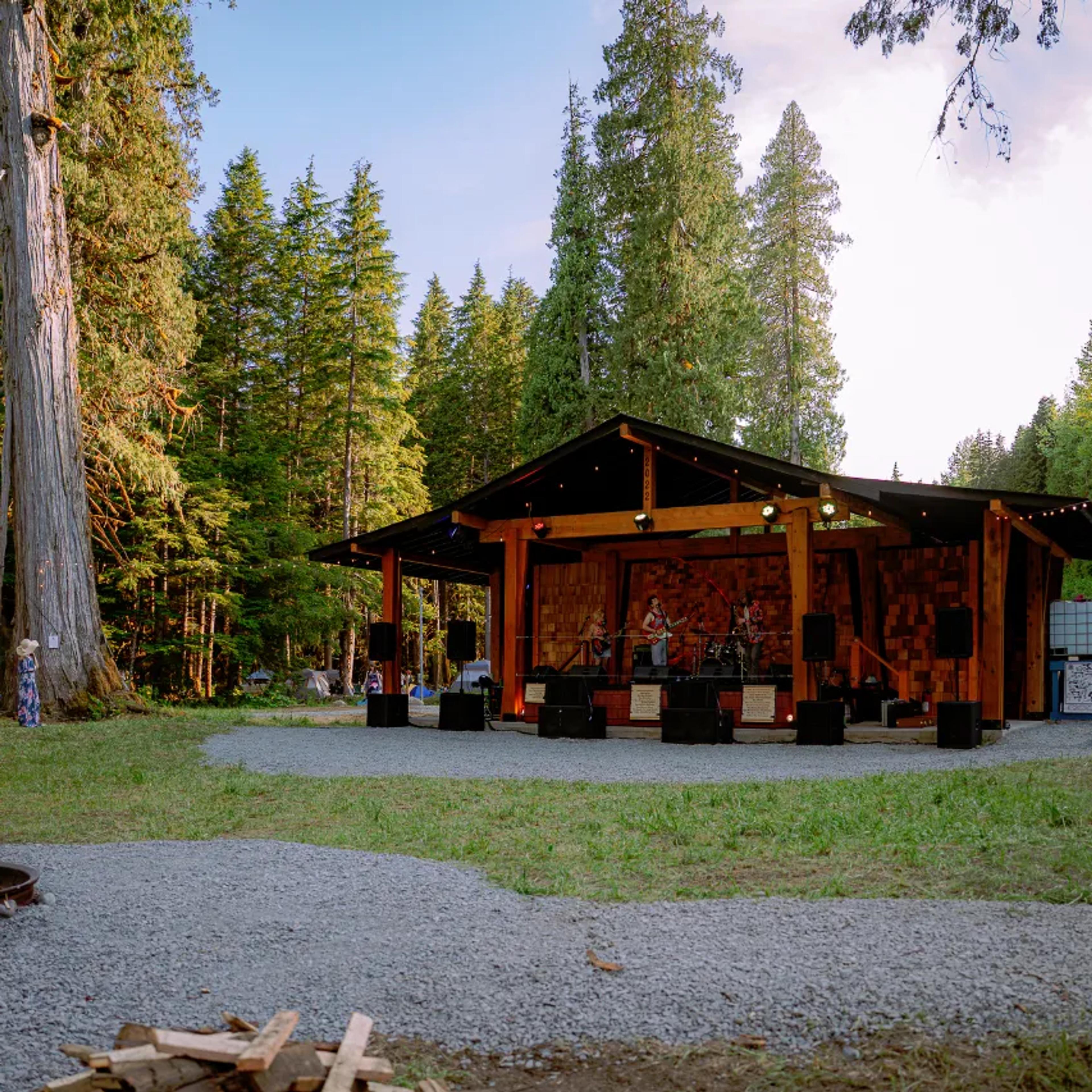 AgeHa stage nestled in forest clearing at golden hour.