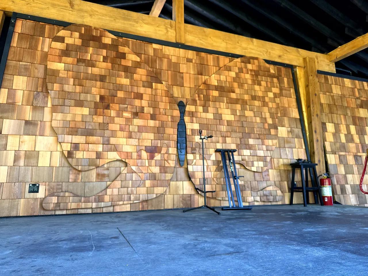 Empty AgeHa stage with backlit butterfly silhouette in cedar shingle backdrop.