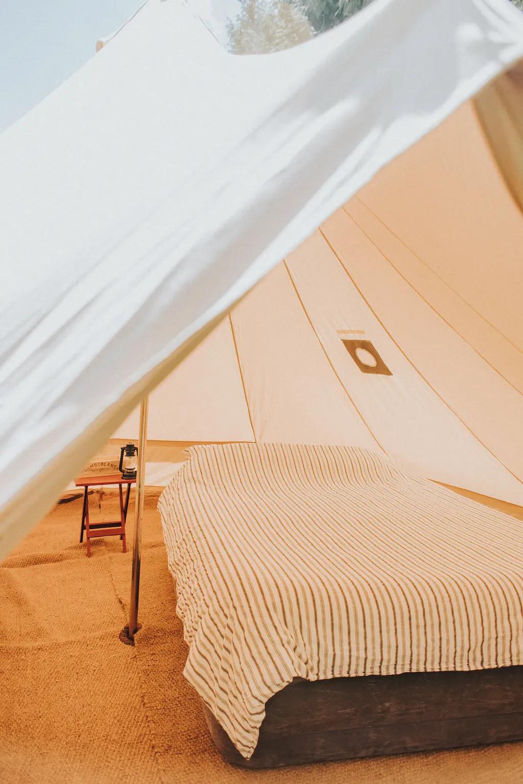 Cozy bed inside a white canvas bell tent