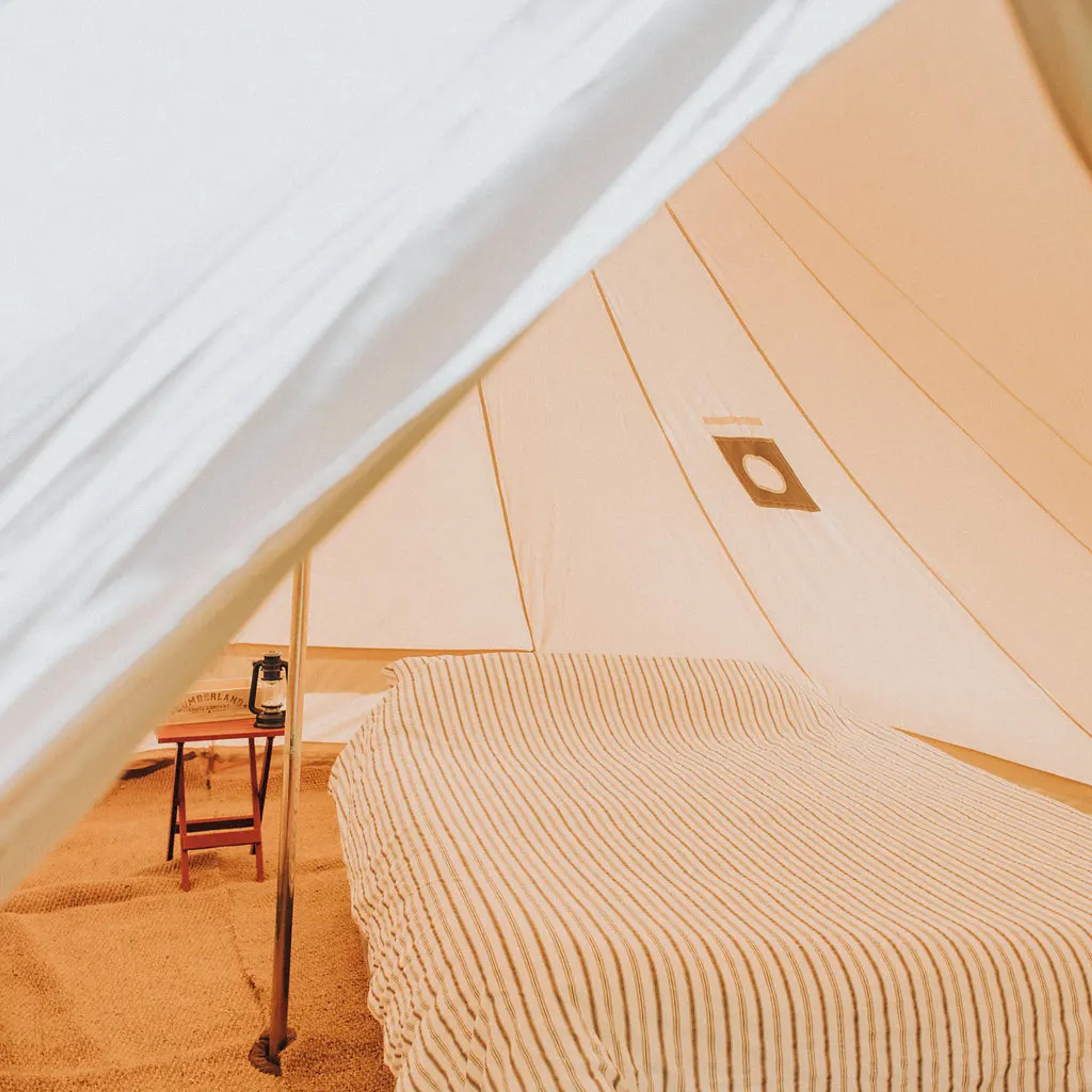 Cozy bed inside a white canvas bell tent