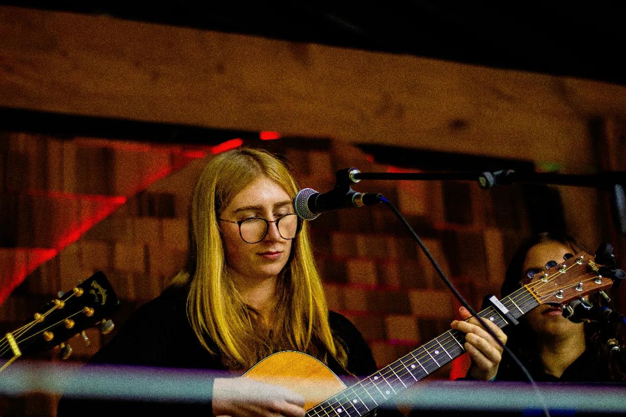 Guitarist performing under warm stage lights at AgeHa night show.