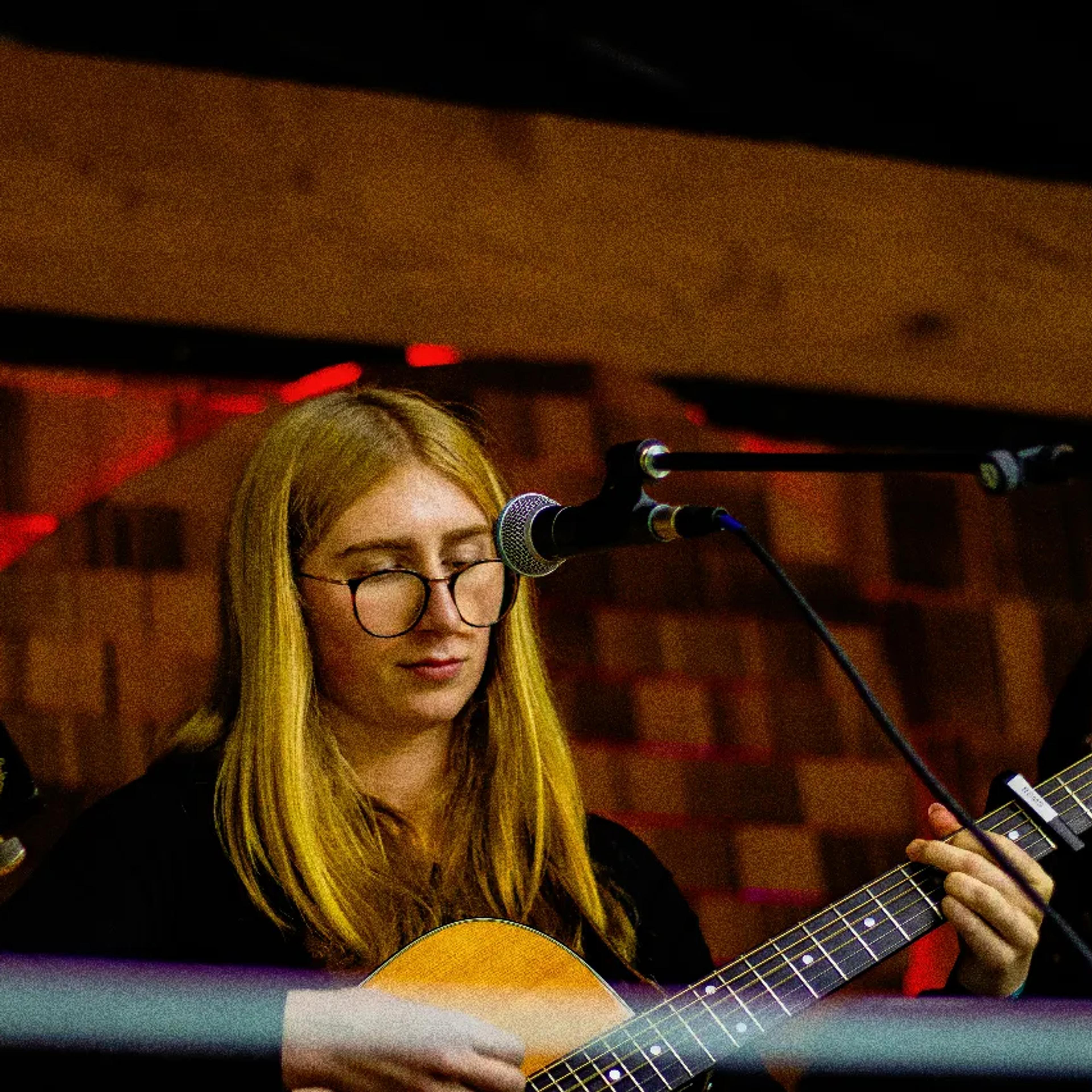 Guitarist performing under warm stage lights at AgeHa night show.