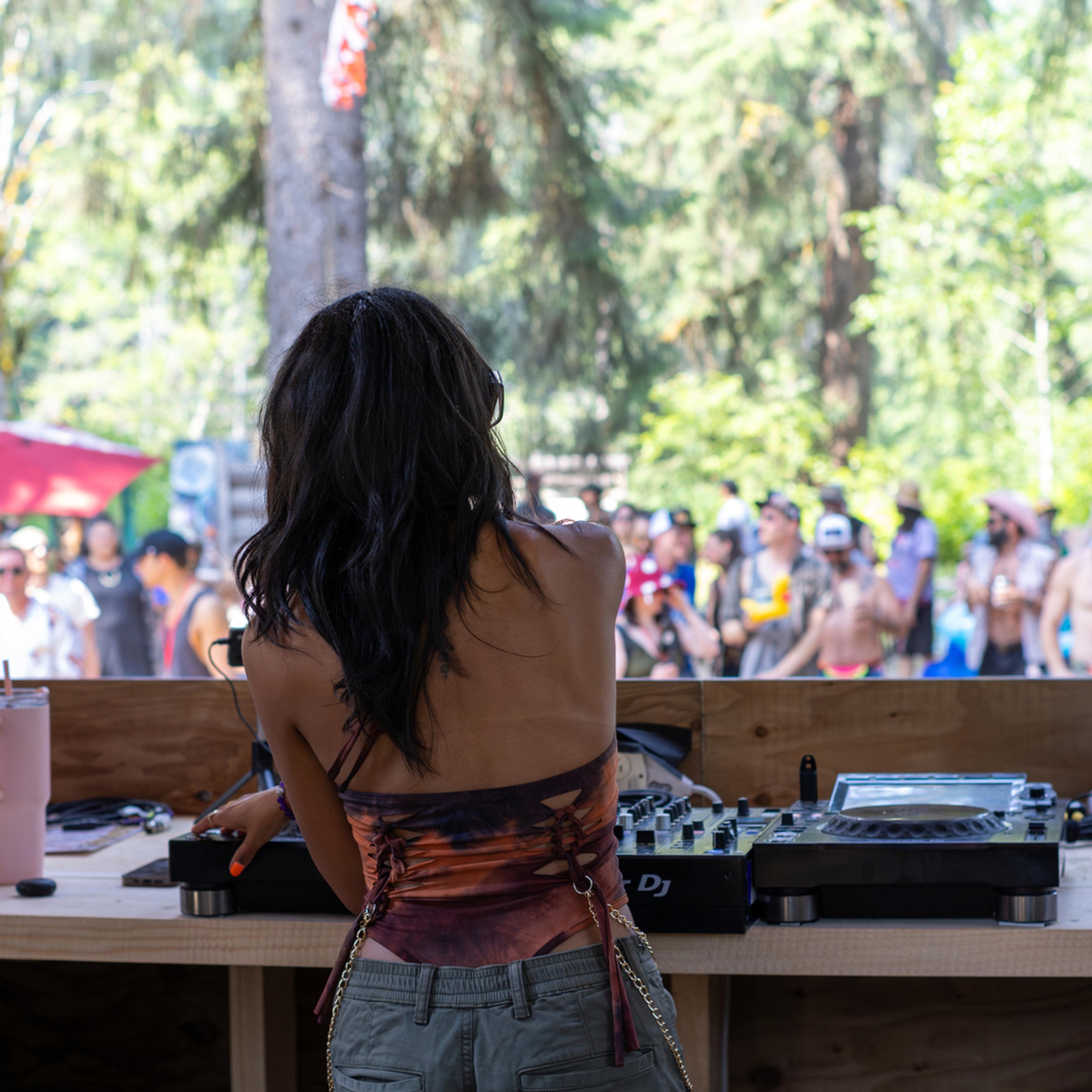 Female DJ performing to outdoor festival crowd