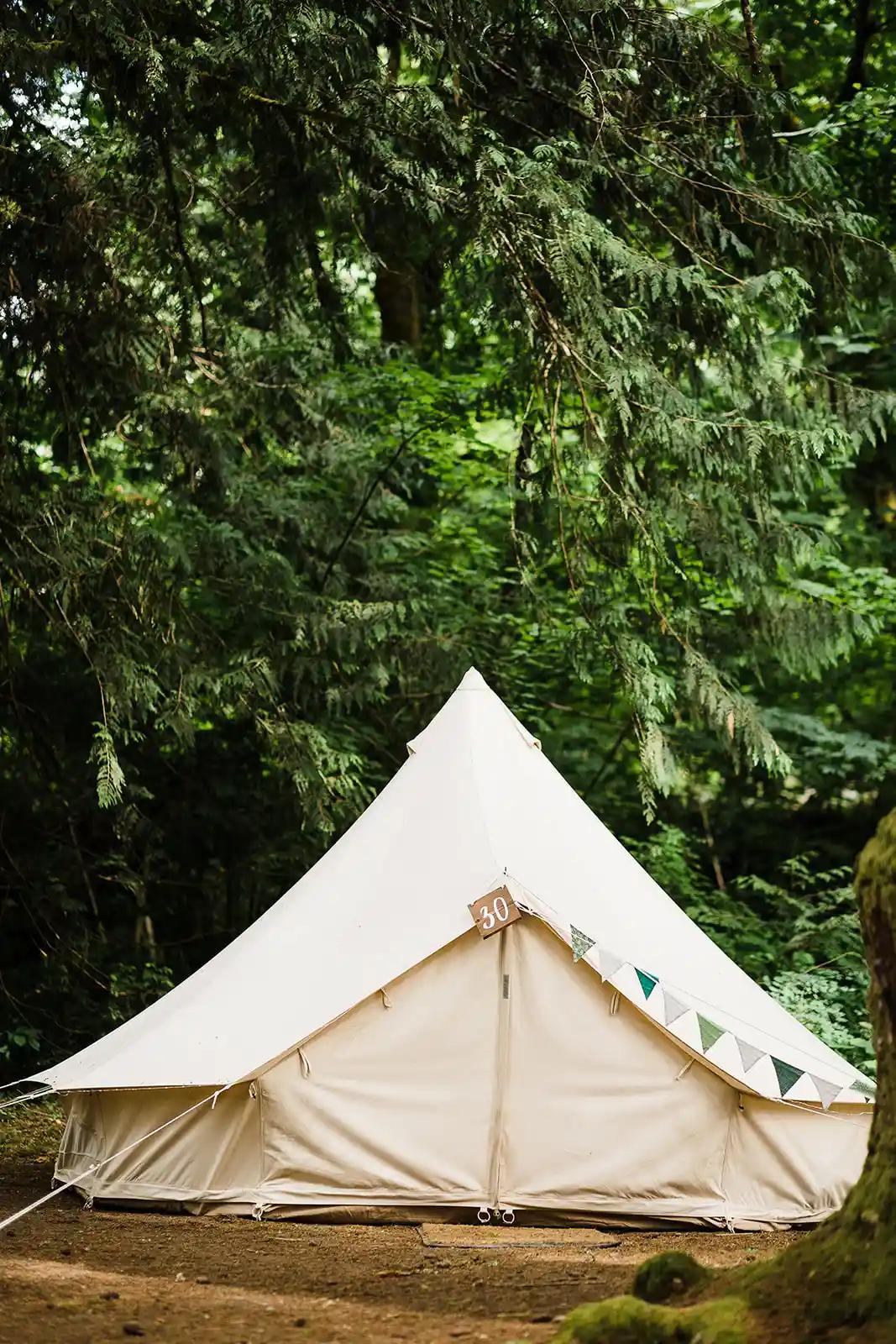 White canvas bell tent set up in a forest