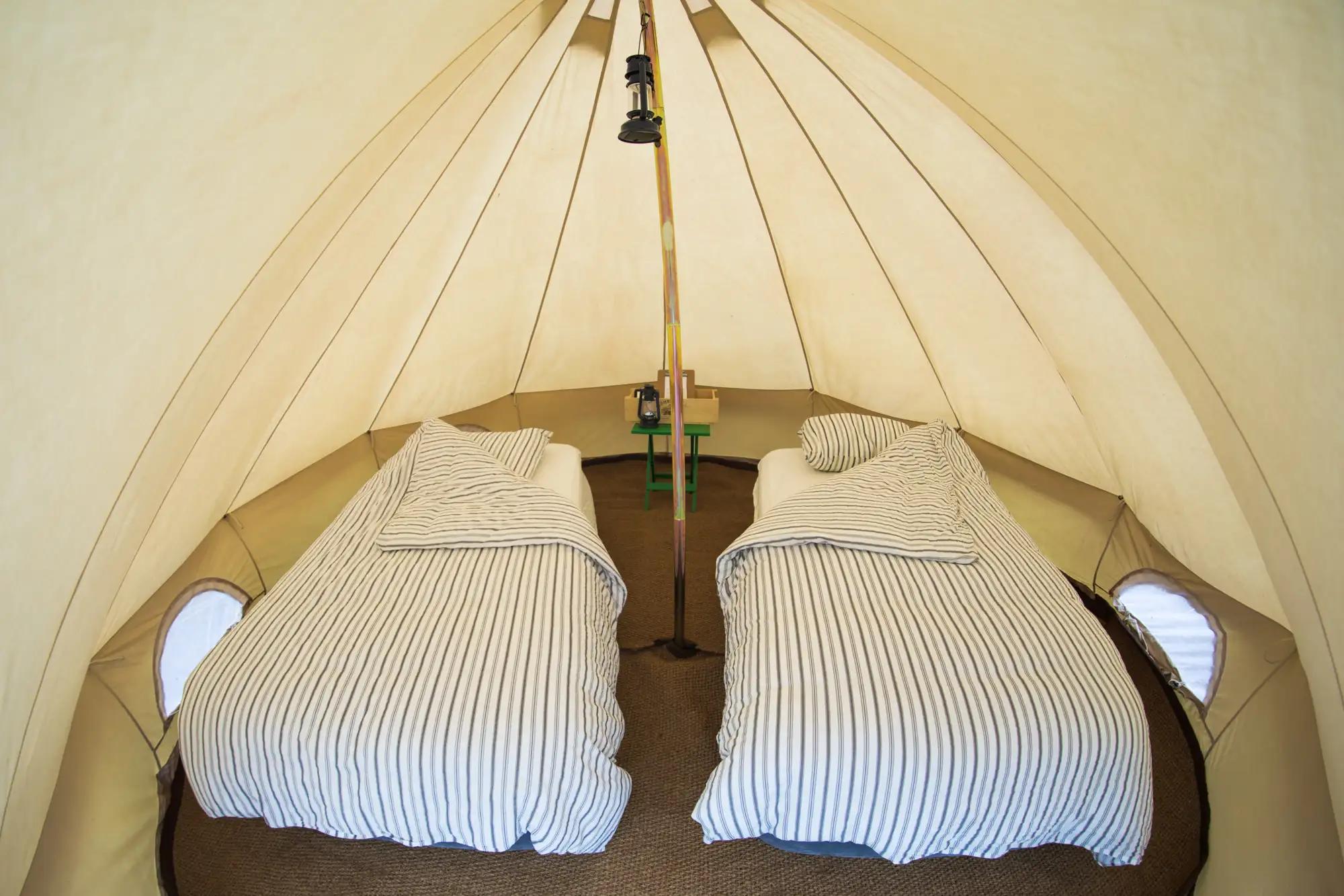 Cozy beds inside a white canvas bell tent