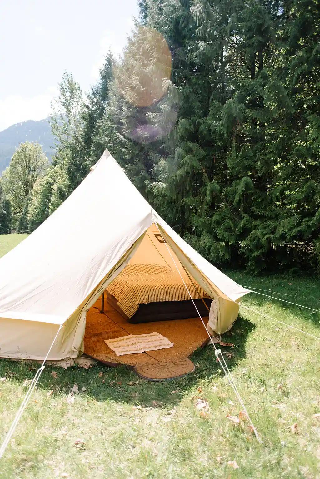 White canvas bell tent set up in a field