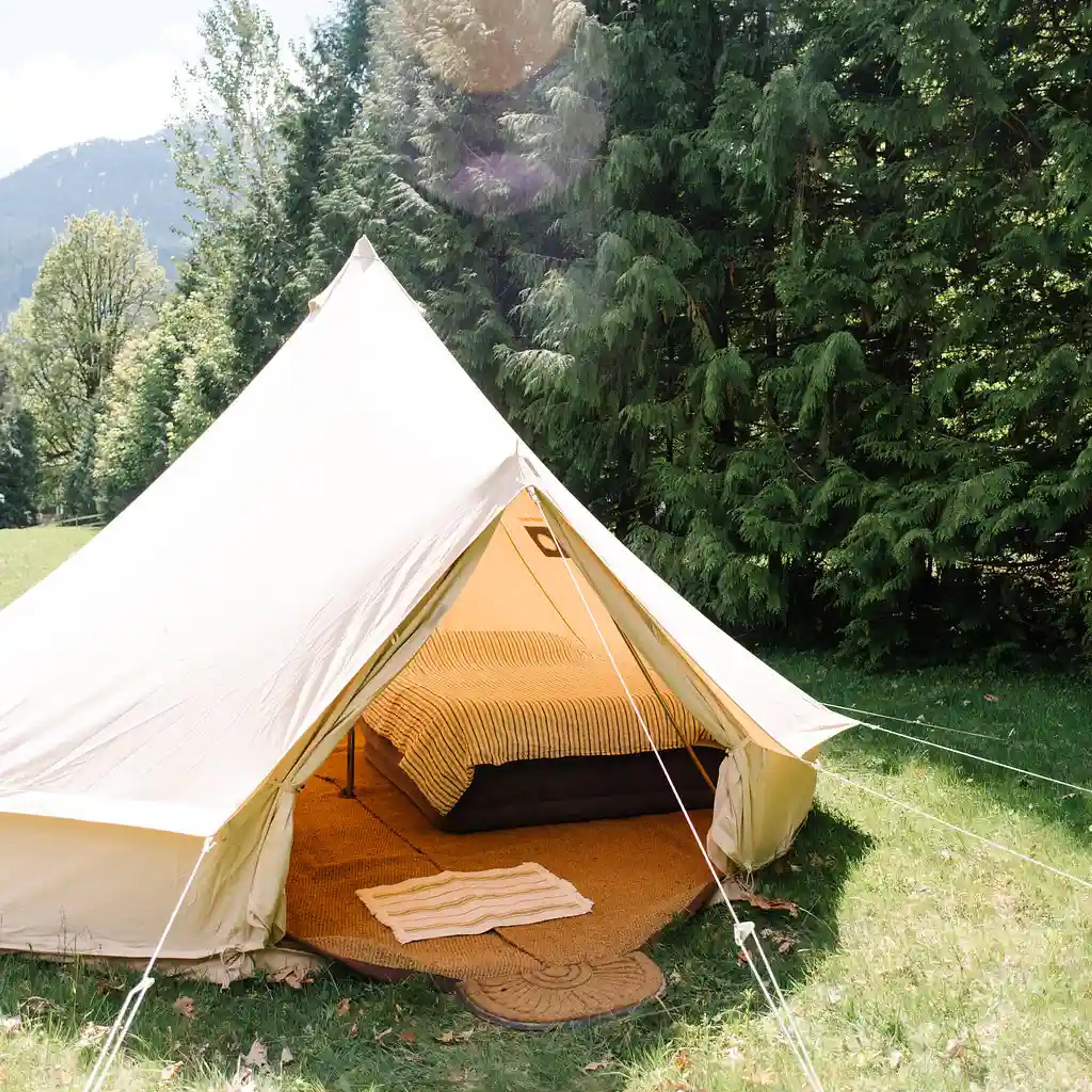 White canvas bell tent set up in a field