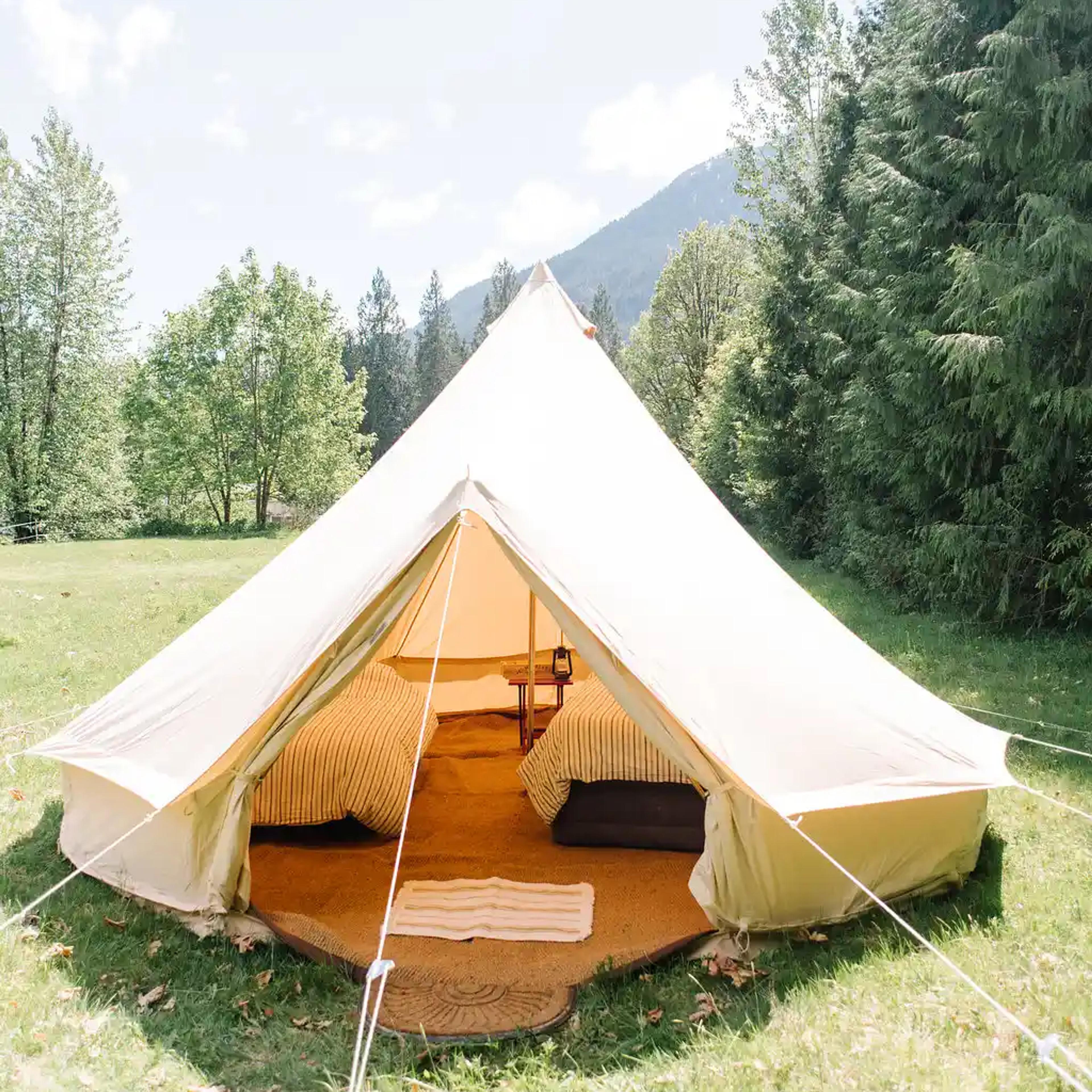 White canvas bell tent set up in a field