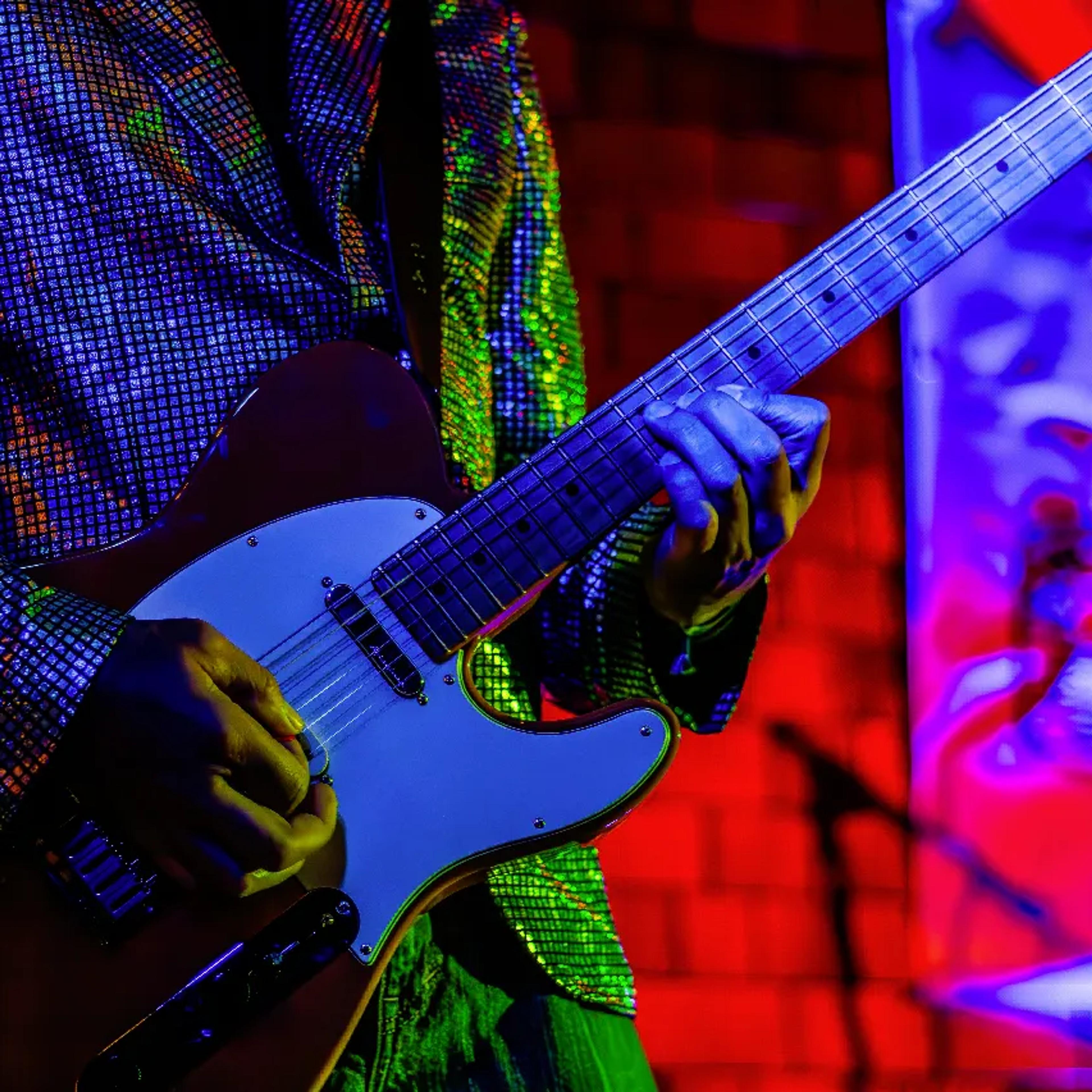 Close-up of electric guitar bathed in blue and red lighting on AgeHa stage.