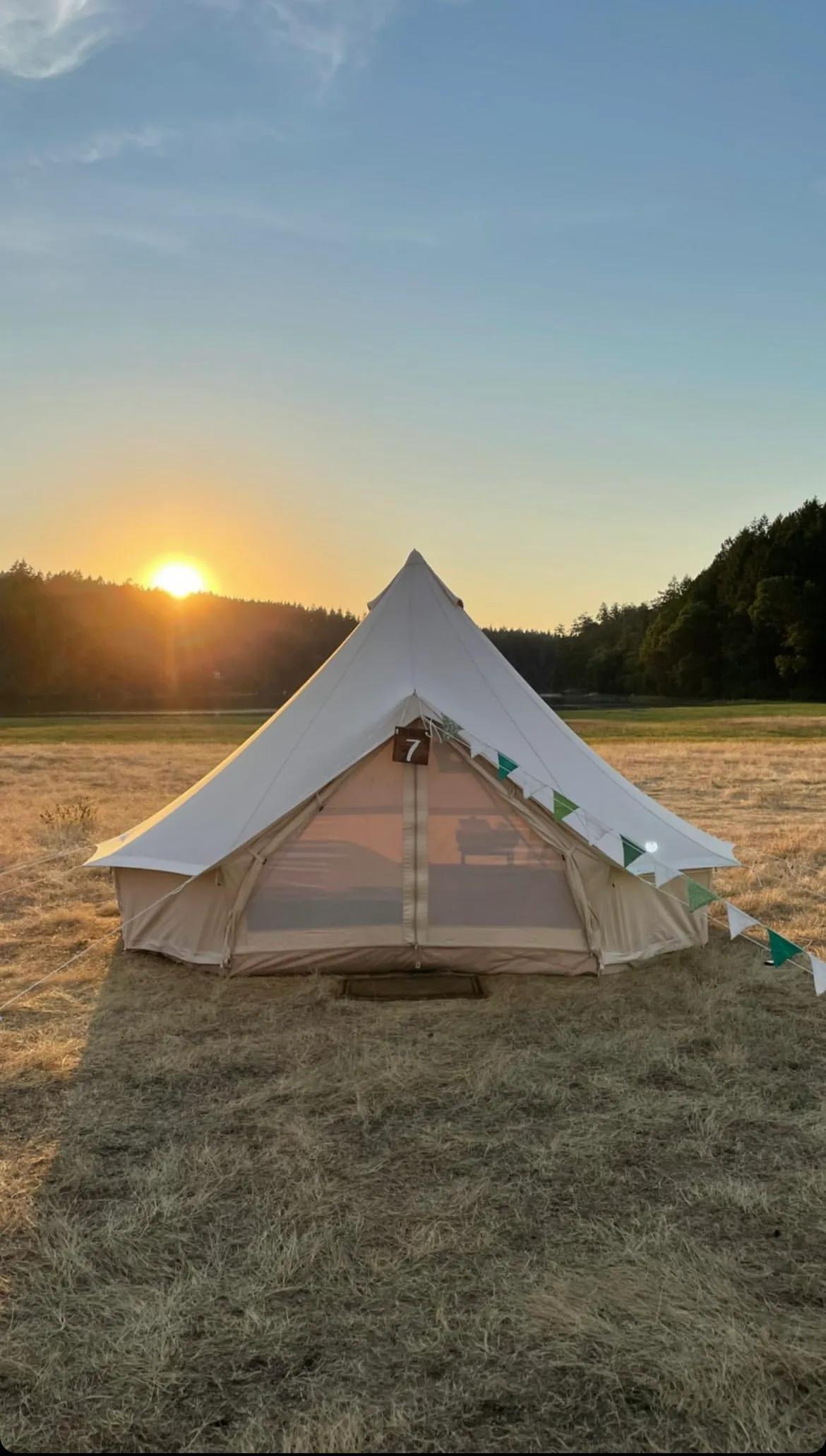 White canvas bell tent set up in a field