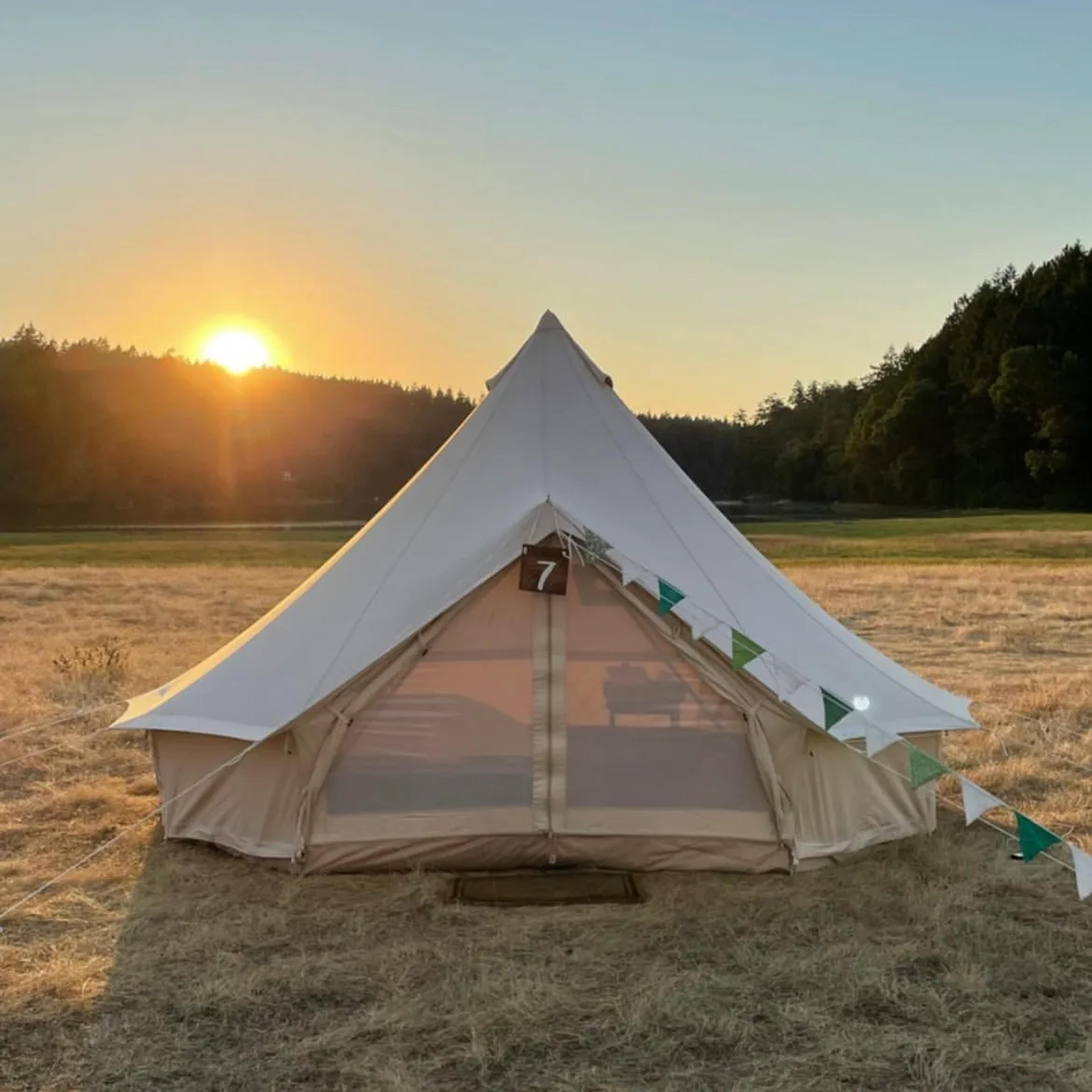 White canvas bell tent set up in a field
