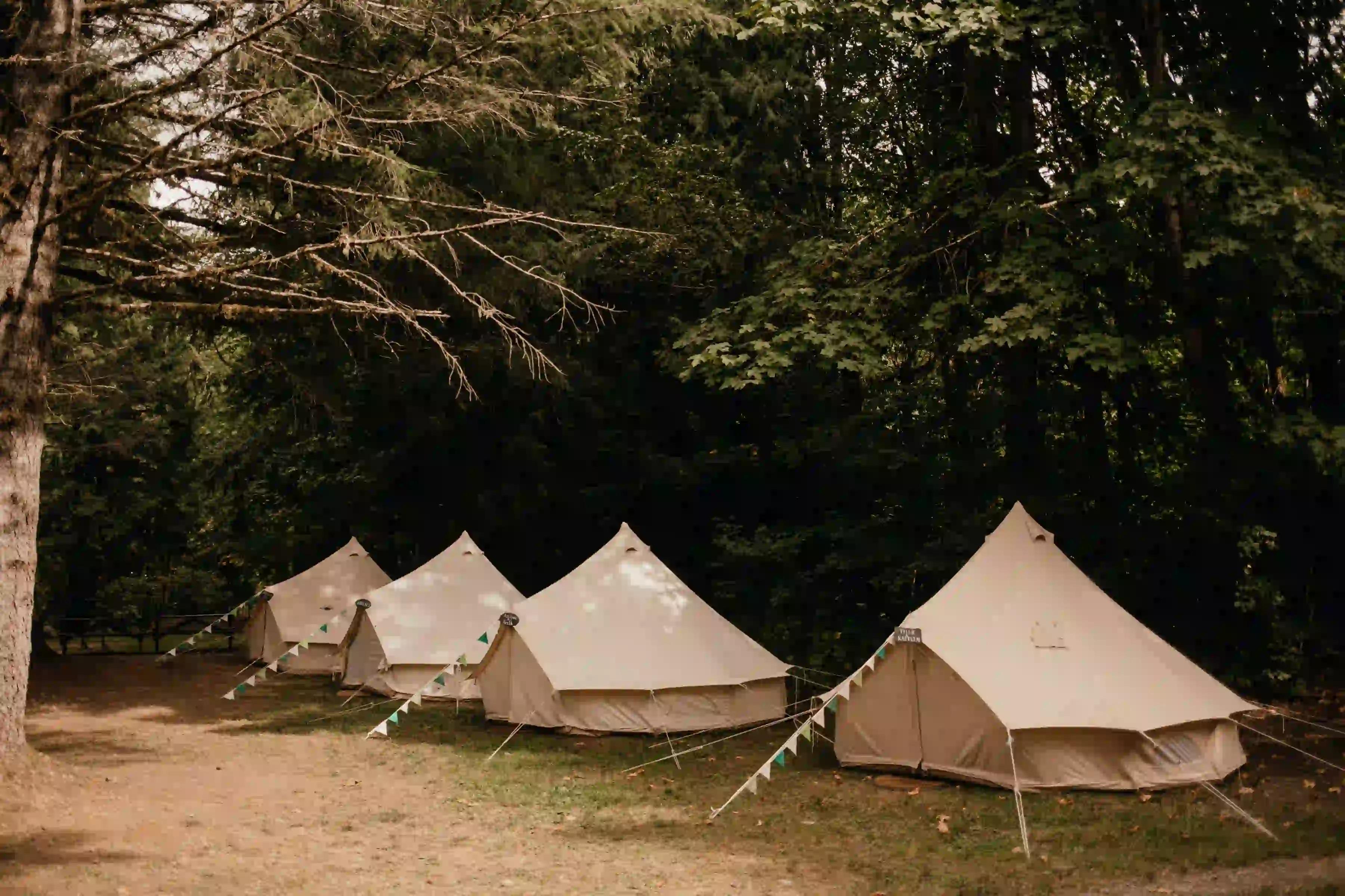 Four white canvas bell tents set up in a row