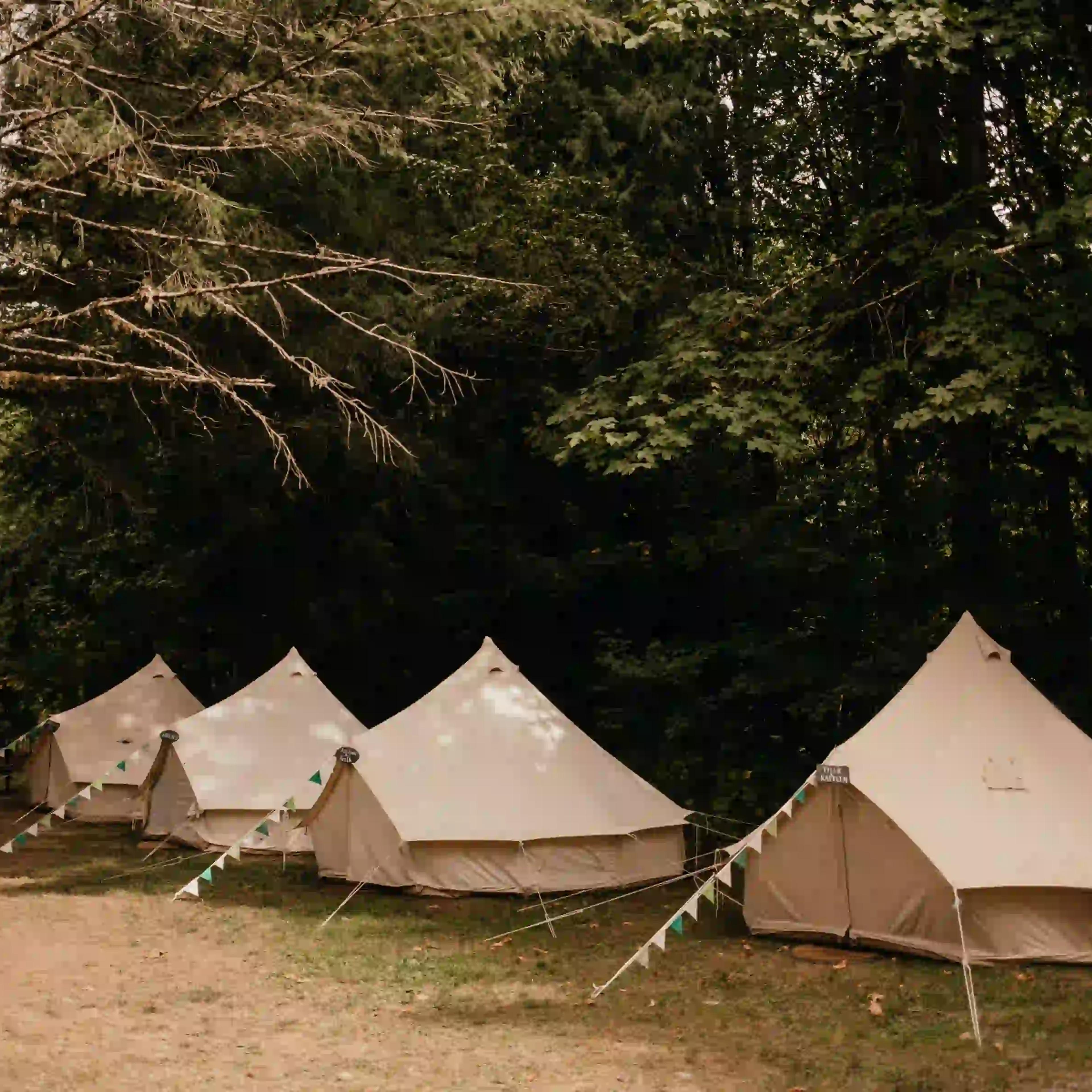 Four white canvas bell tents set up in a row