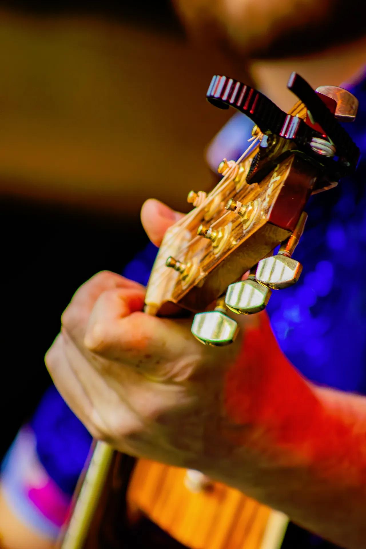 Close-up of AgeHa guitarist's hand on acoustic guitar neck with capo attached.