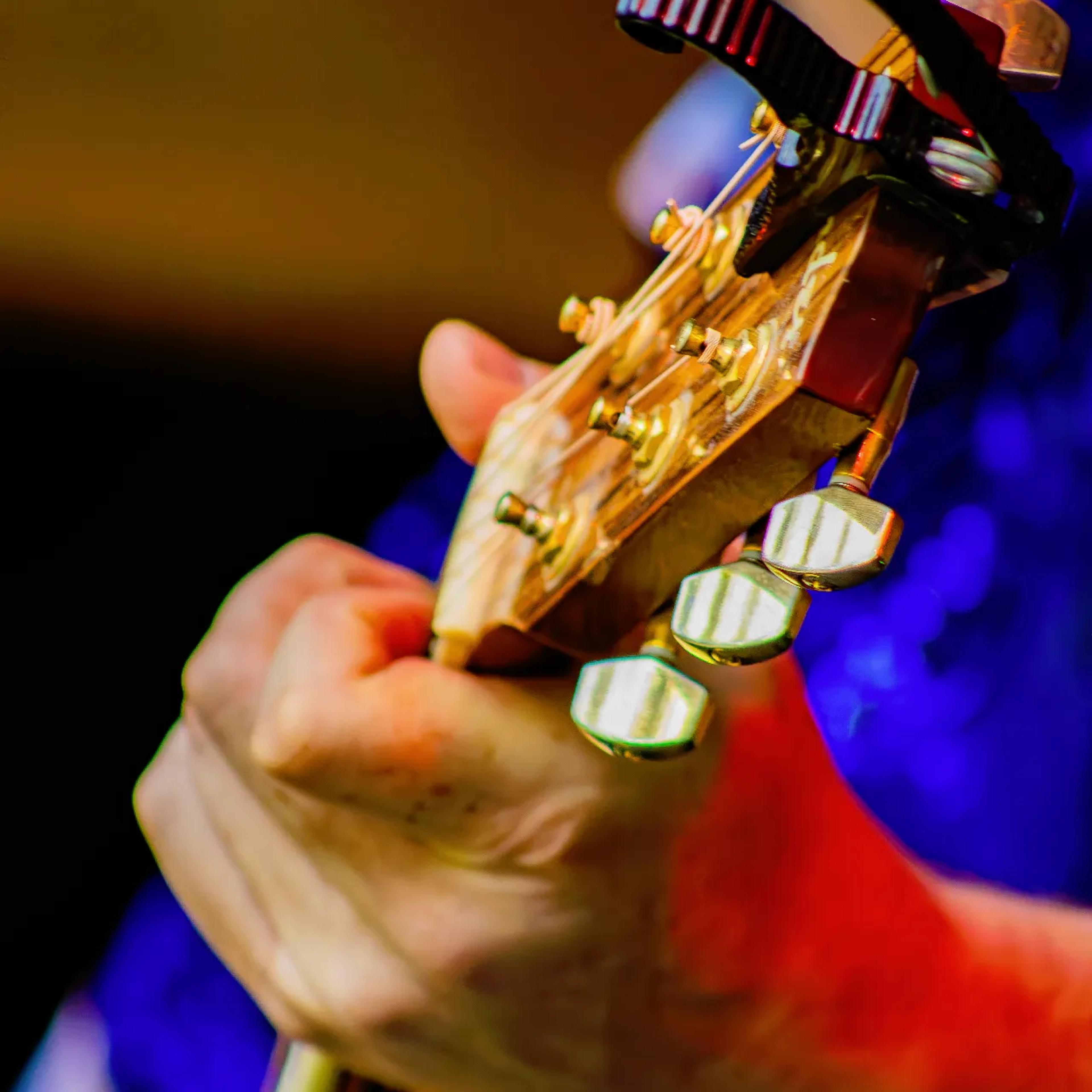 Close-up of AgeHa guitarist's hand on acoustic guitar neck with capo attached.