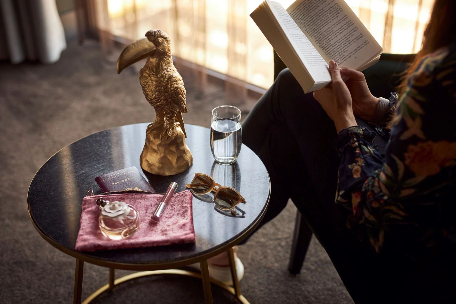 Gold toucan on a coffee table beside someone reading