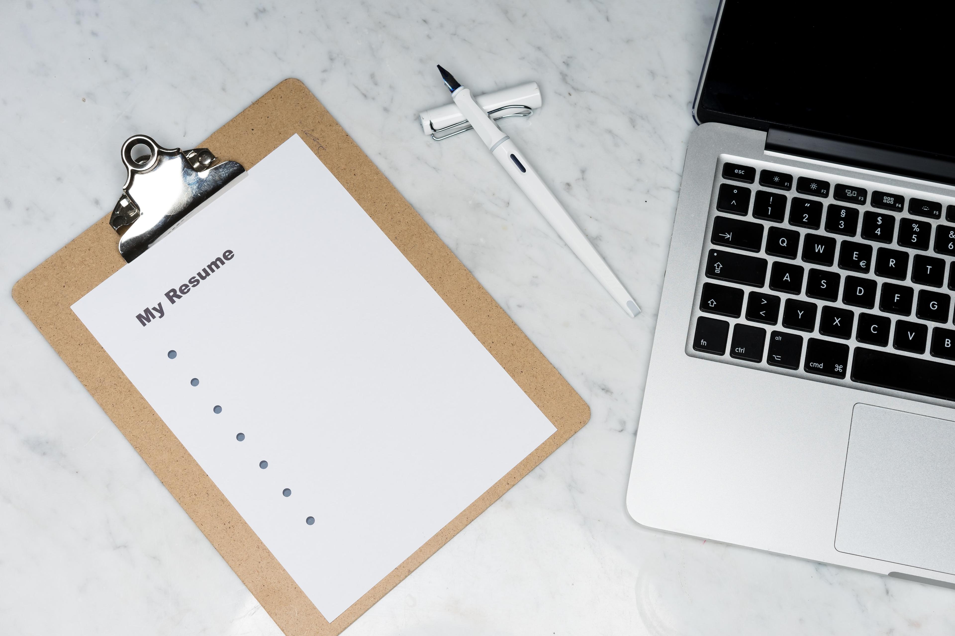 A notepad on a desk besides a laptop.