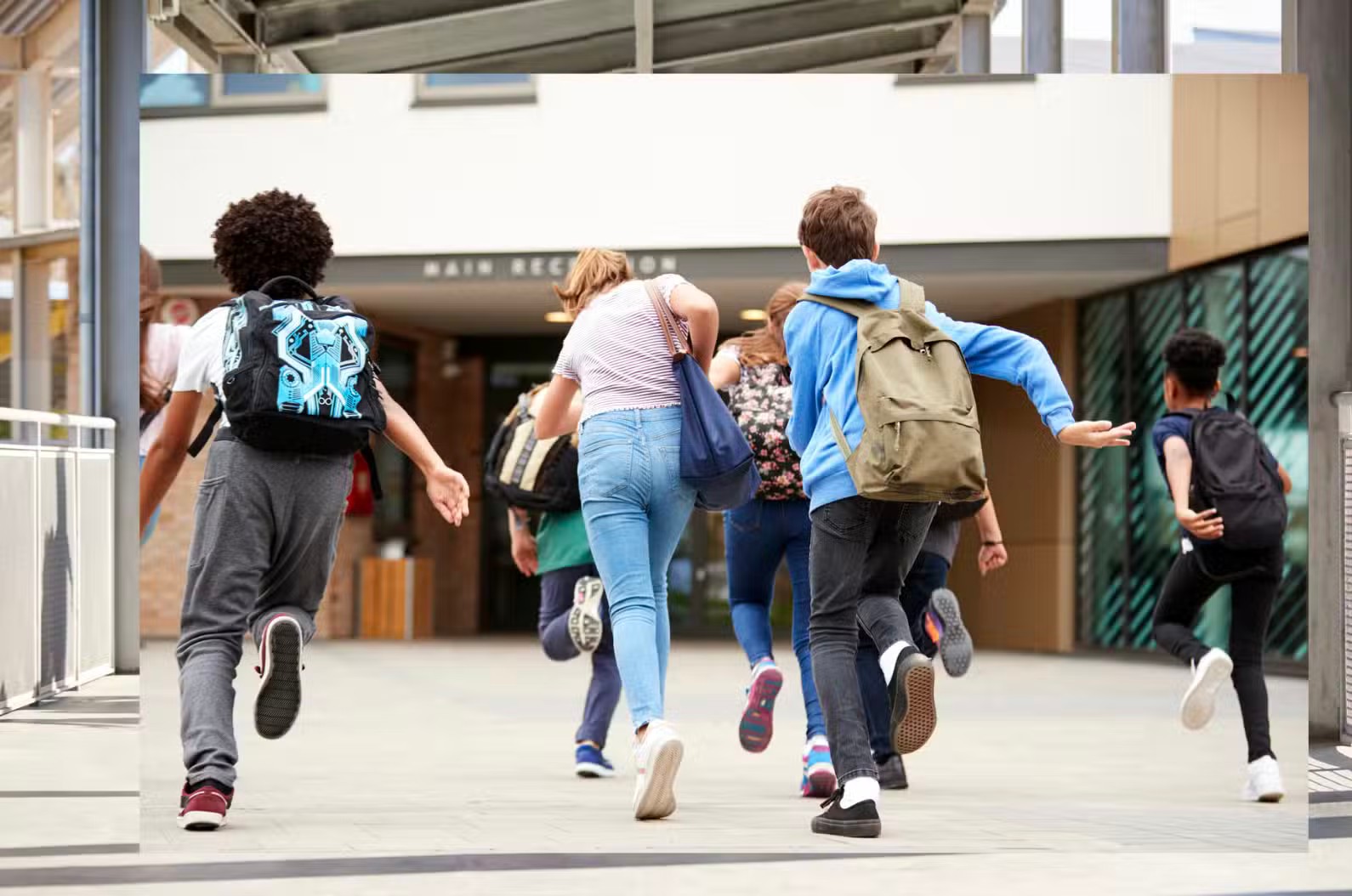a group of children are running out of a school building .