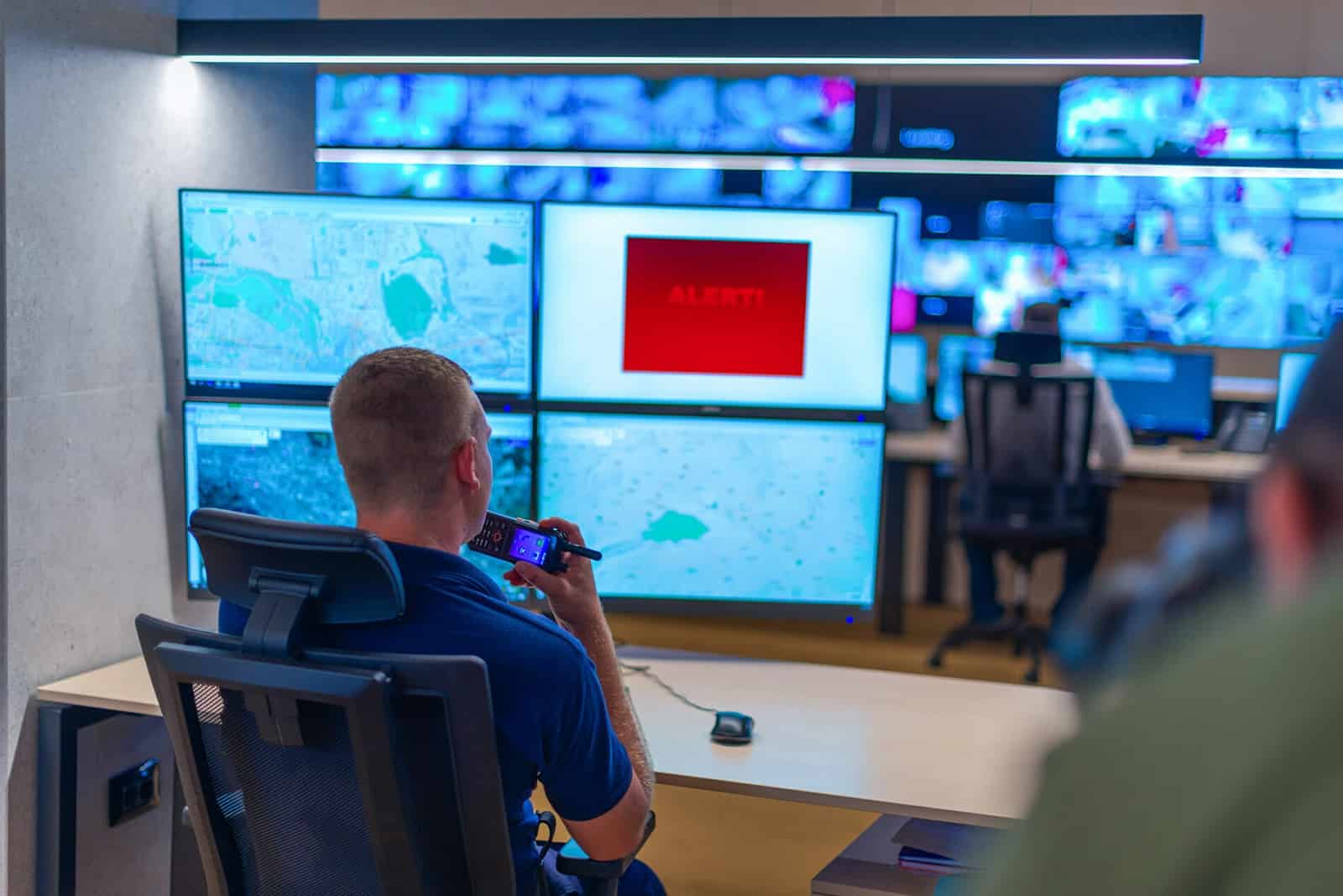a man is sitting at a desk in front of a monitor in a control room .